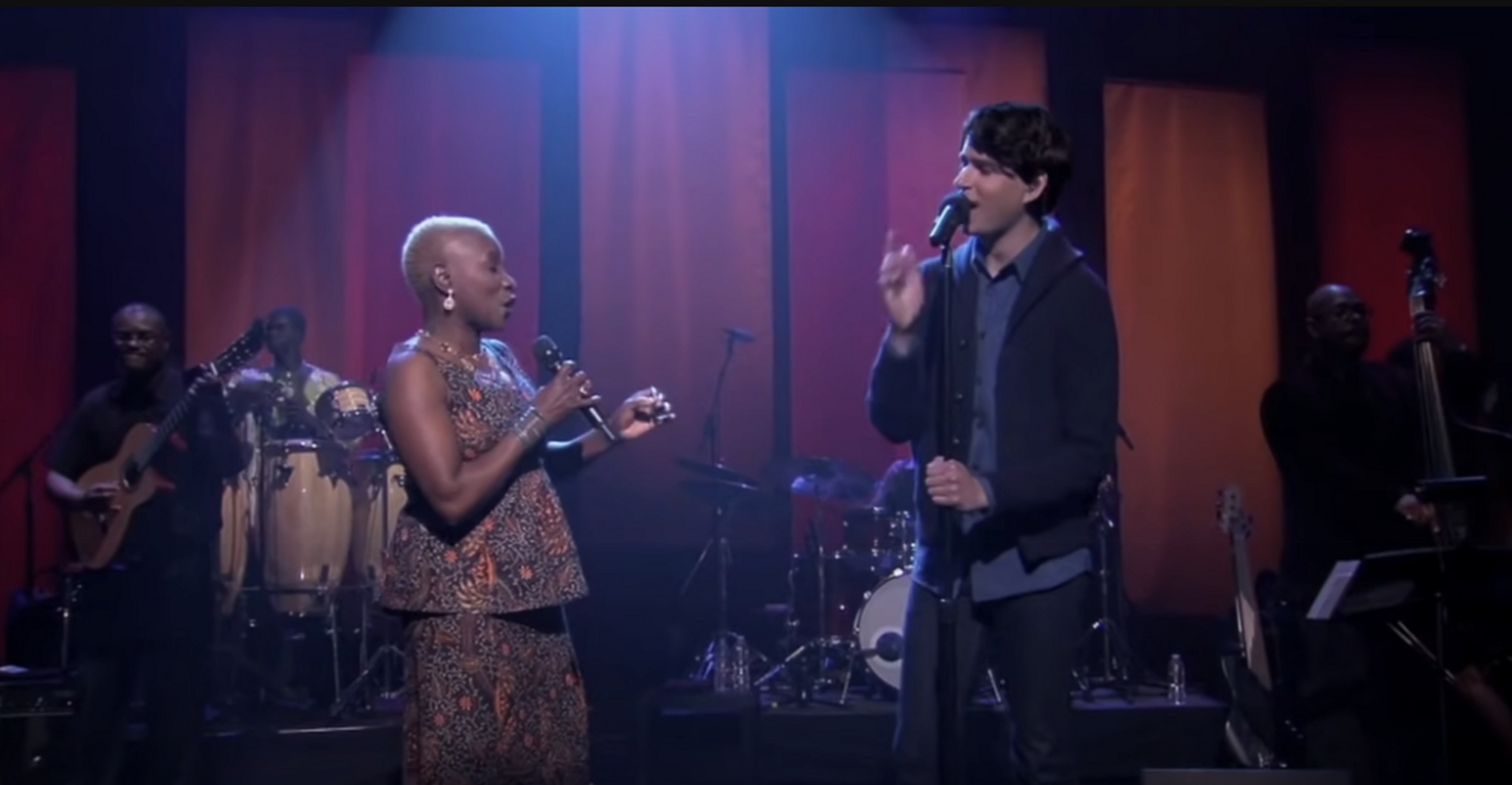 A black woman and a white man singing onstage
