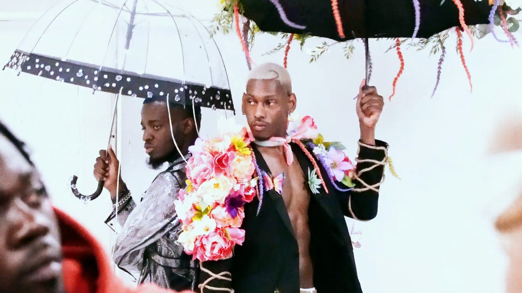 Two men holding umbrellas decorated with flowers at a ballroom