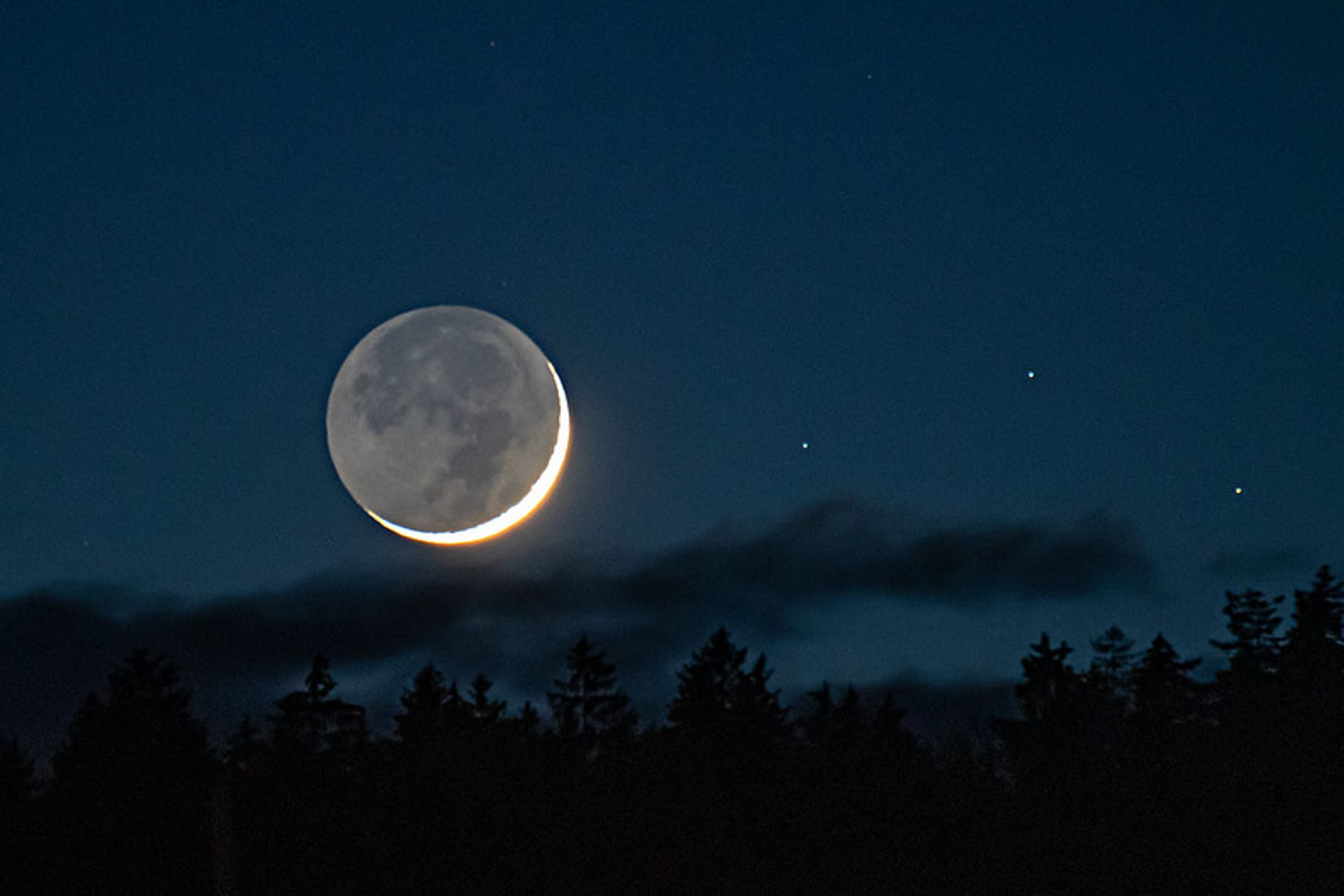Earthshine moon against a dark blue sky