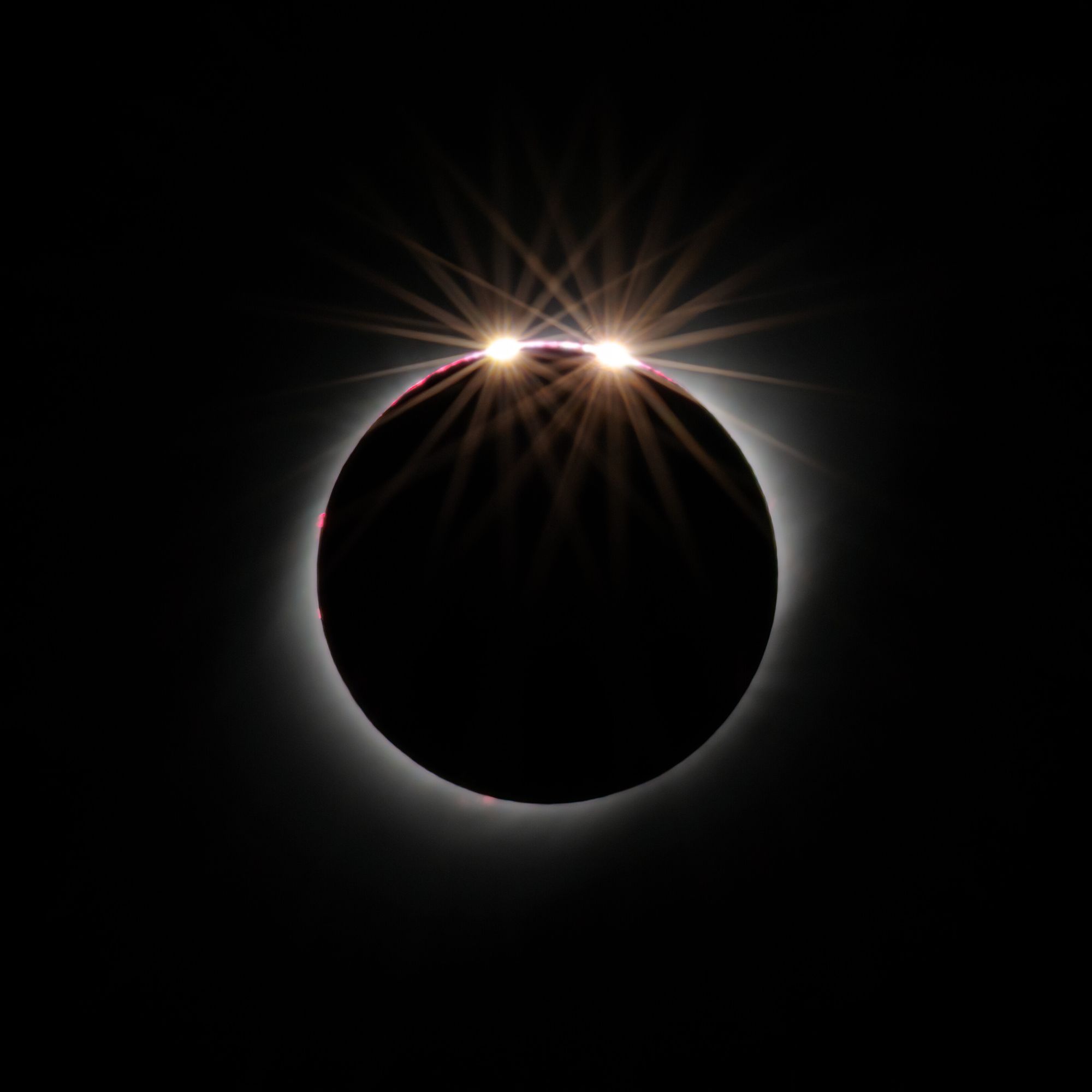 A total eclipse, with two bright bead-like dots of light appearing from the top corner.