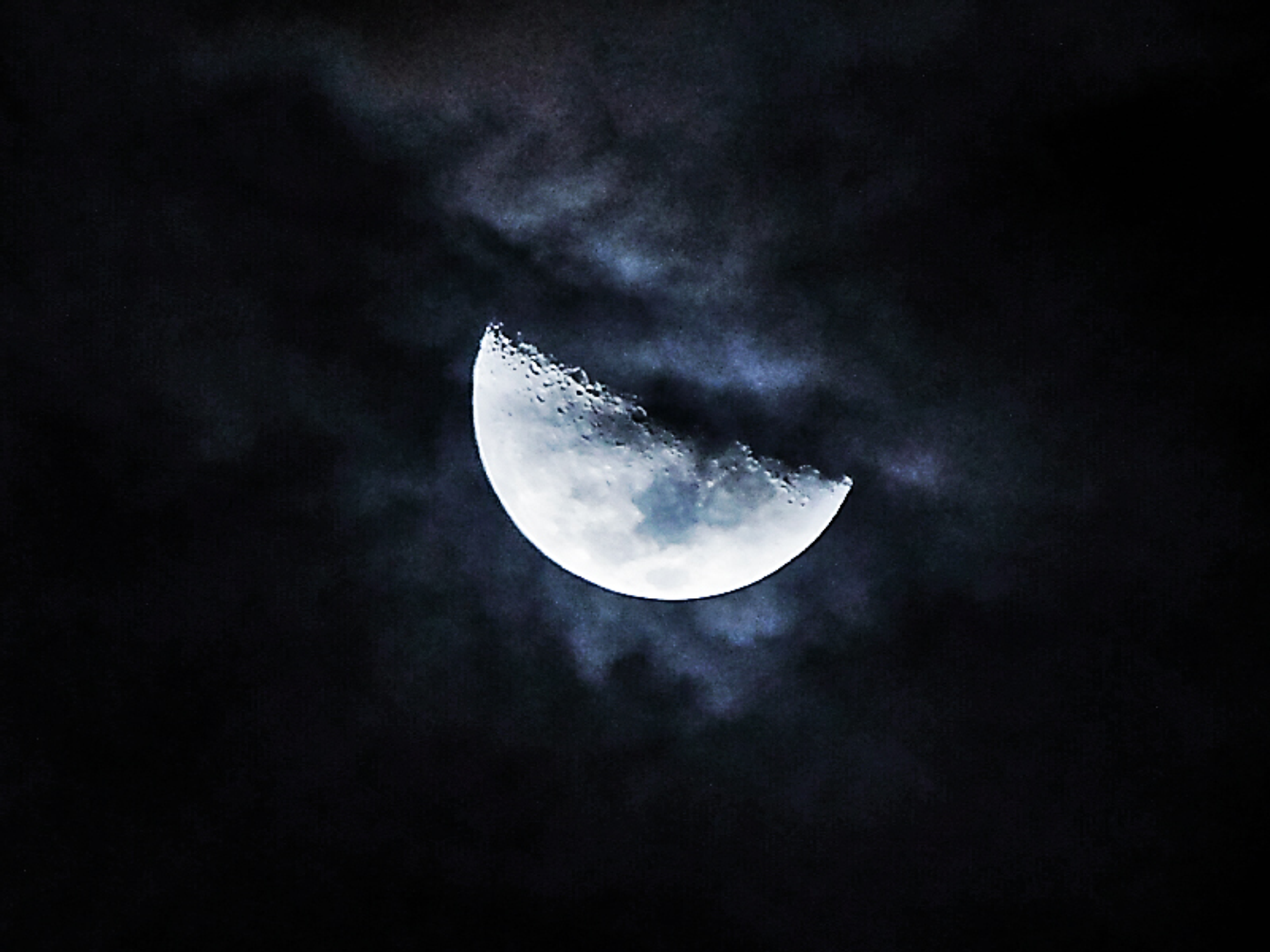 Blueish quarter moon in black space 