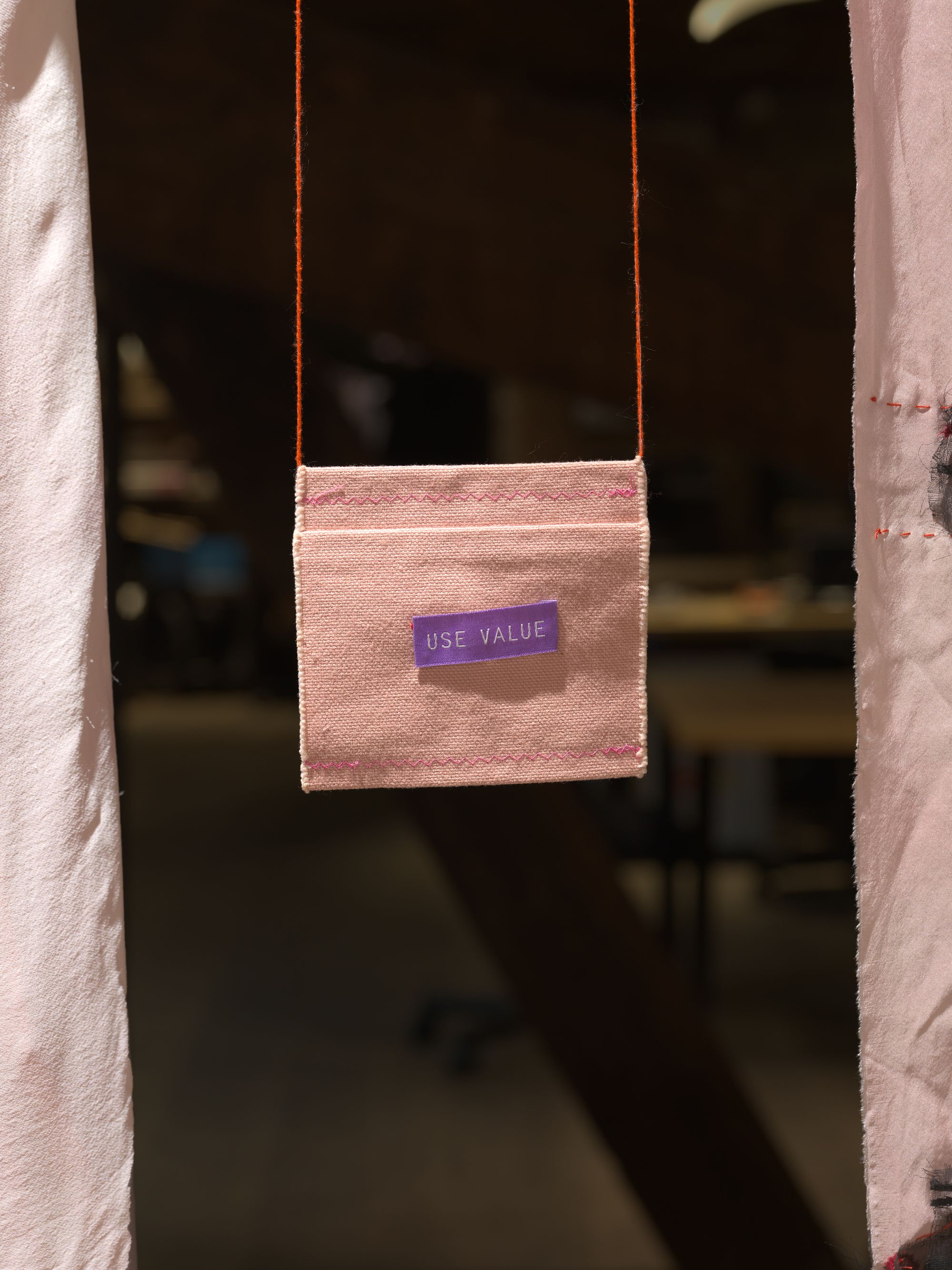 A small pouch hanging, with a label sewn on its front that reads "USE VALUE"