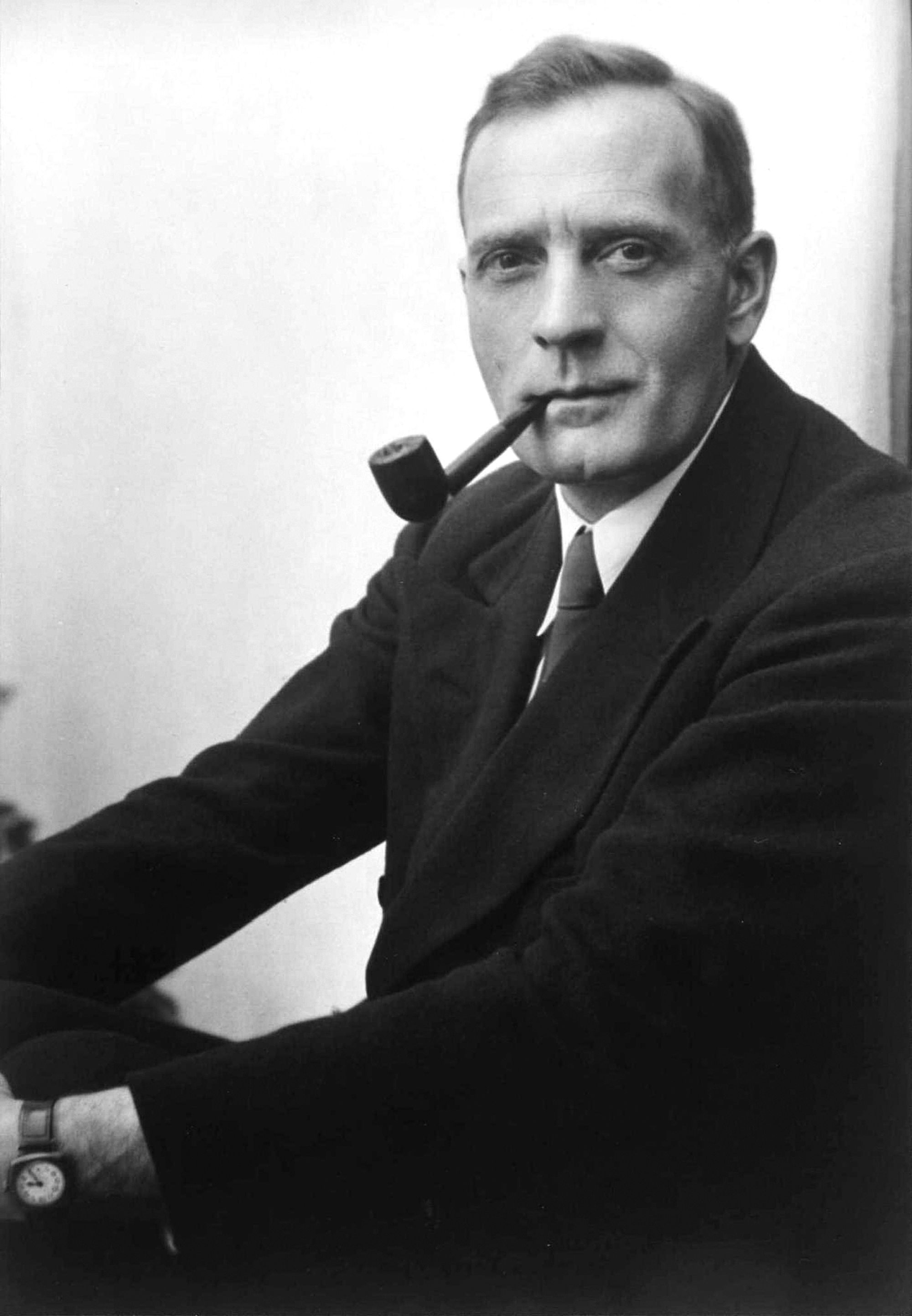 A black-and-white portrait of a young Hubble with a pipe in his mouth.