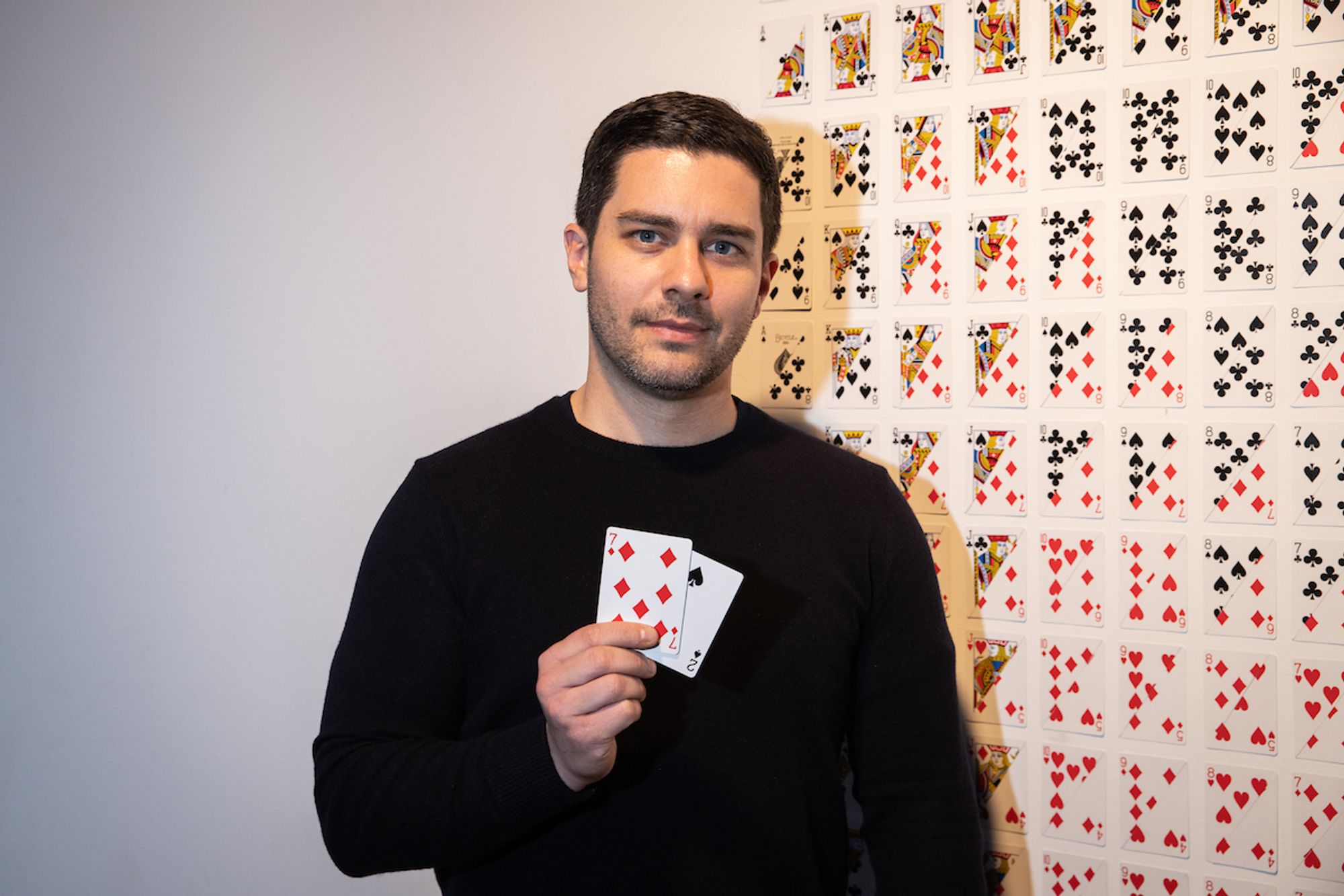 White man holding playing cards