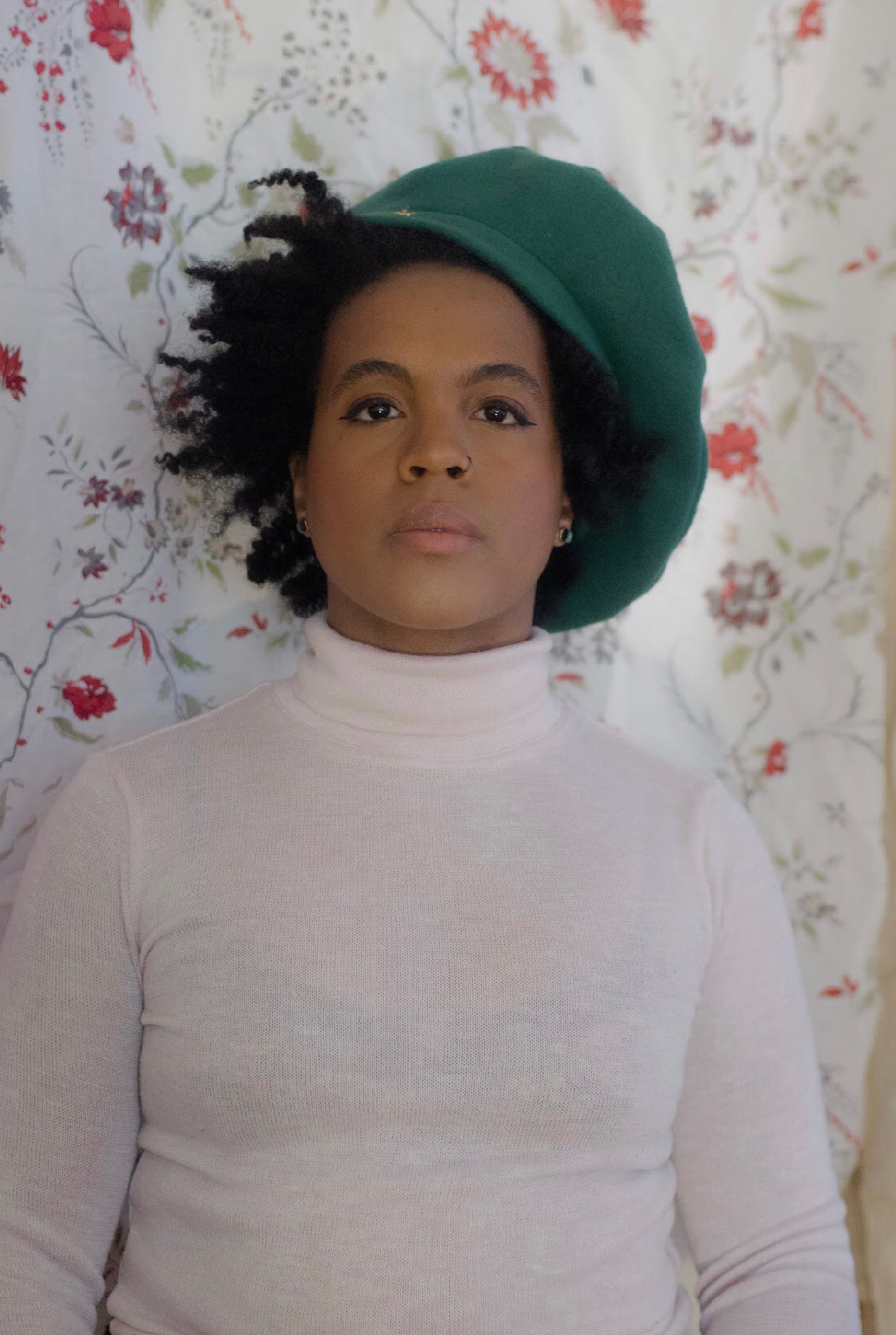 Black woman with a green hat and white sweater.
