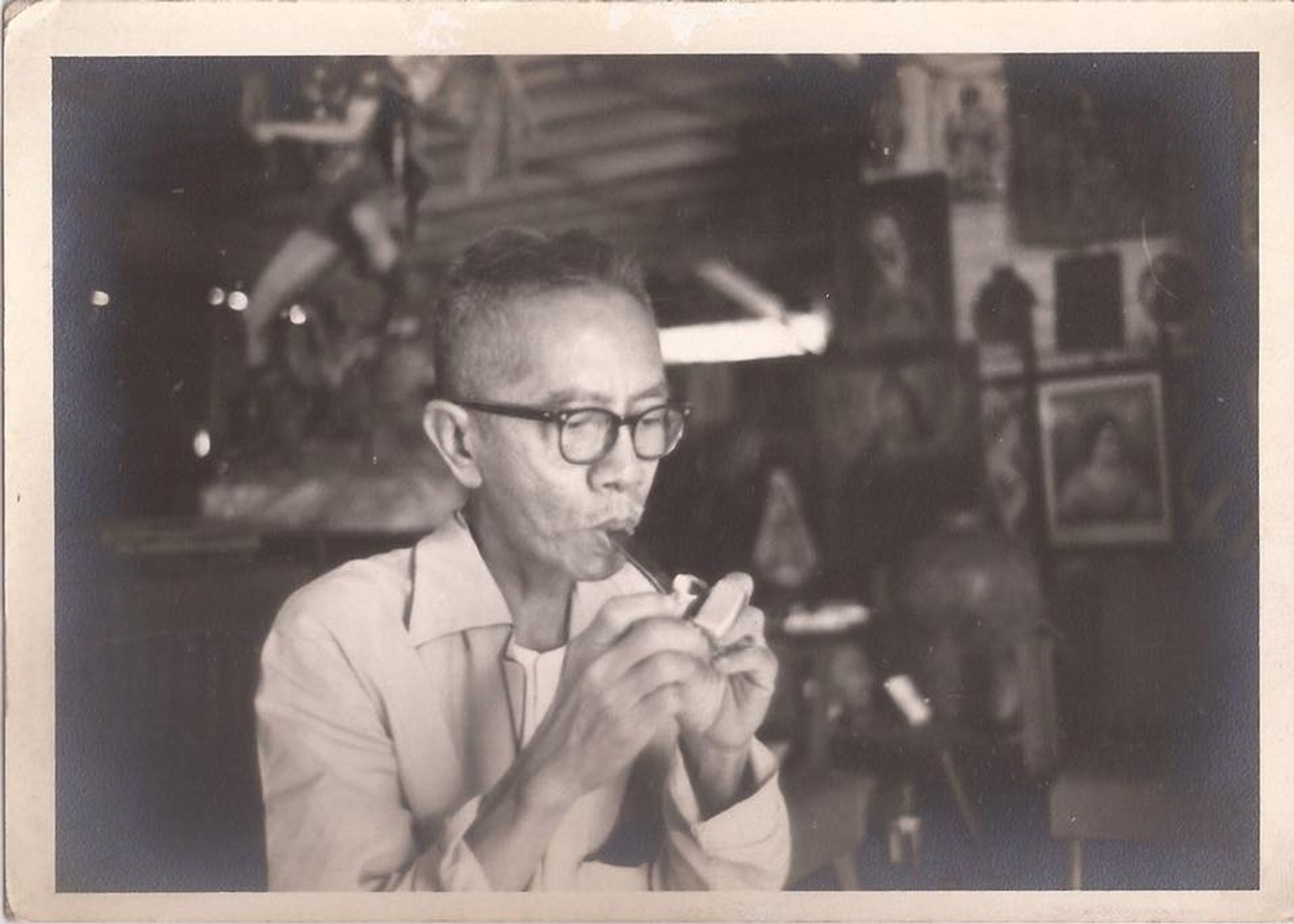 A photograph of Protomartir in old age. He is wearing black-rimmed glasses and a collared jacket. He is in the middle of lighting a pipe.