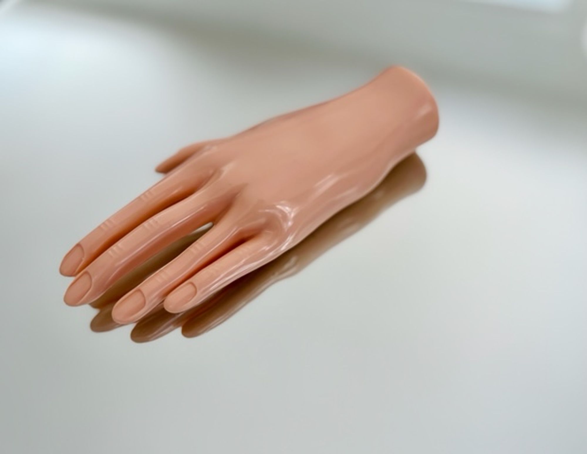 A pink, glossy rubber hand on a piece of glass