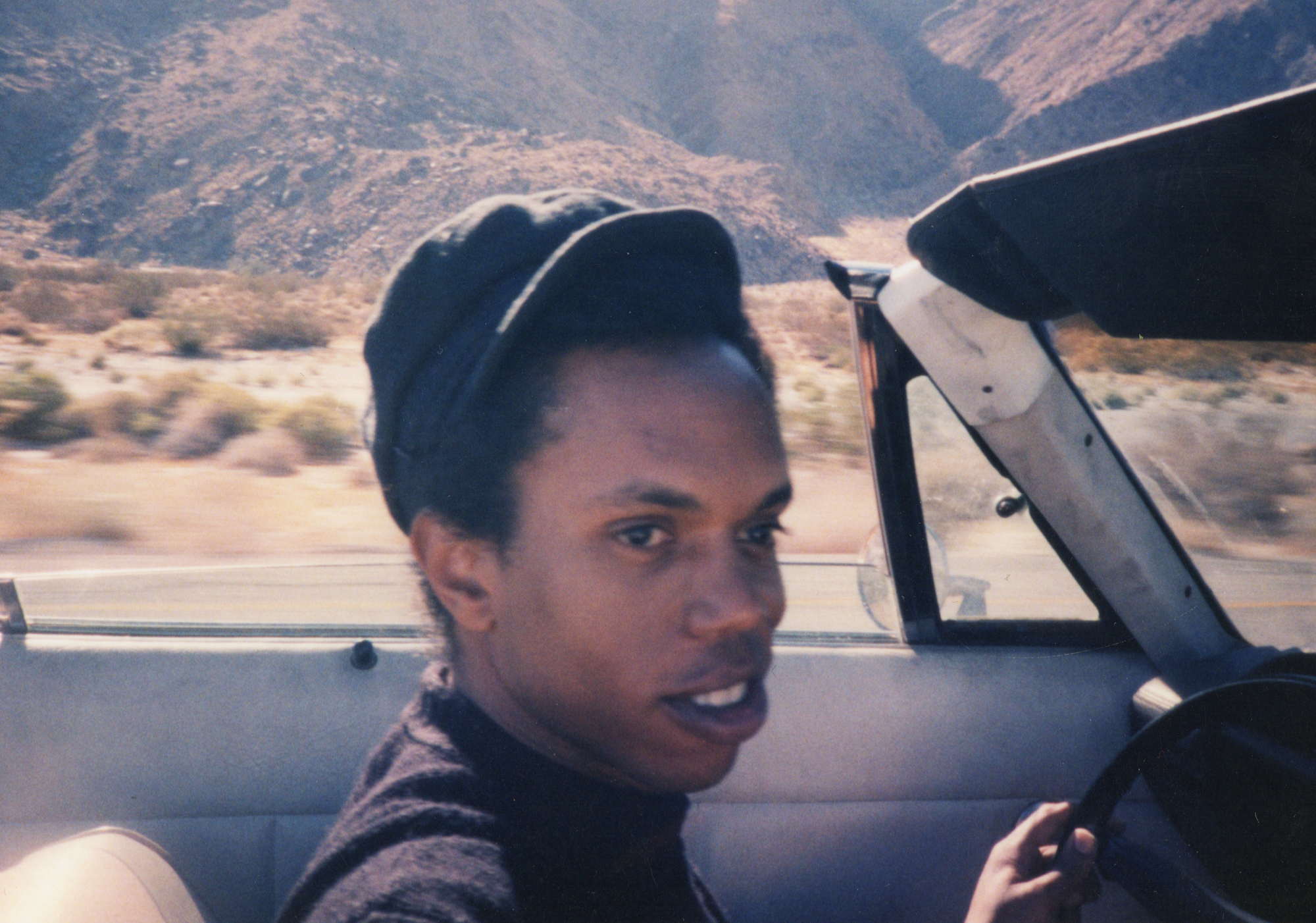 A young man driving through a Californian desert.