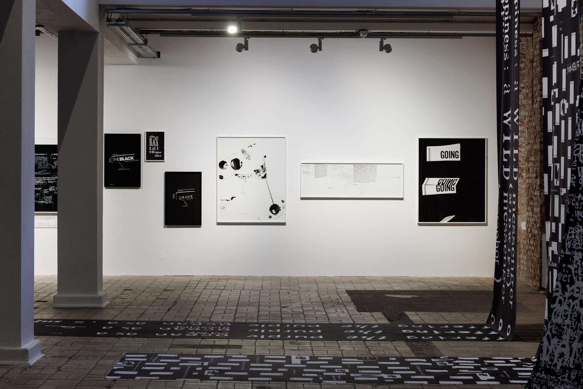 An installation view of white and black paintings on a white wall.