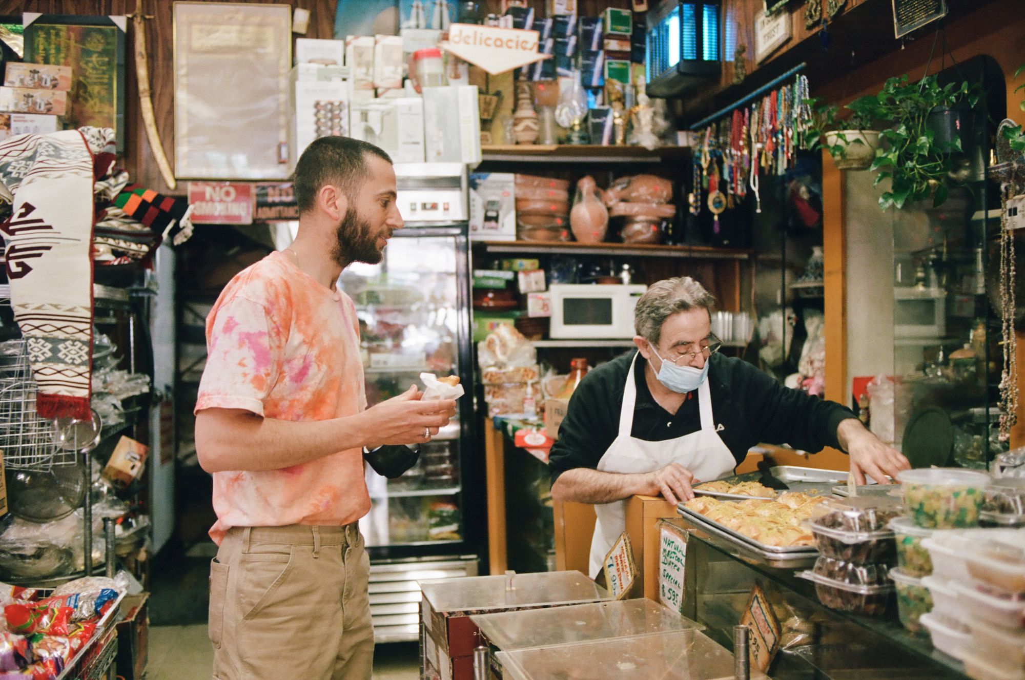 Loren Abramovitch and man in mask confer over pastries.