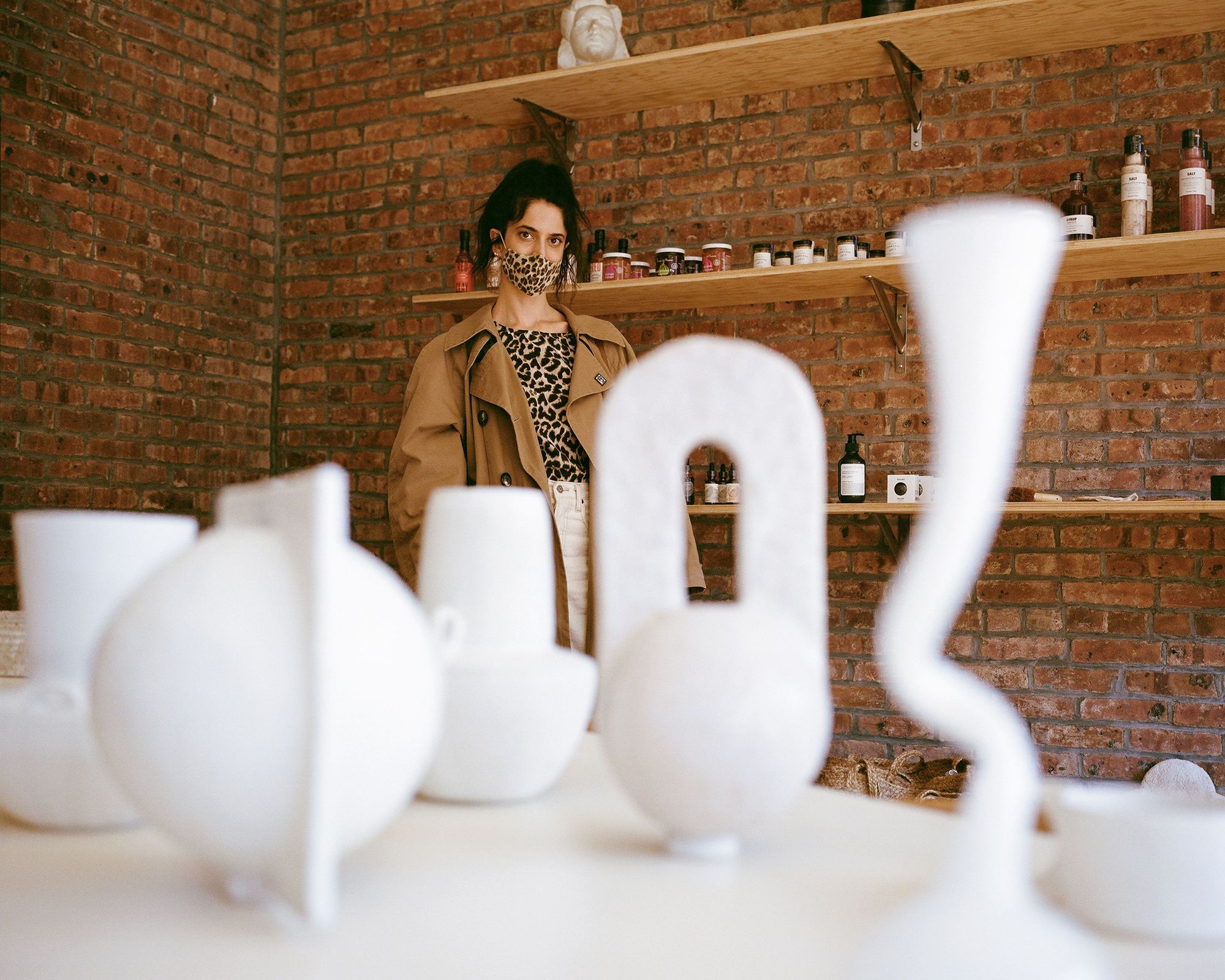 Anna Polonsky posing in front of sculptural vases at Raini Home in bedford-stuyvesant