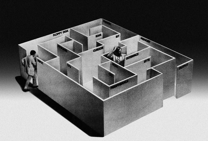 Two figures stumble through a maze that resembles a cubicle in scale and material, juxtaposed against a dreamlike black-and-white landscape