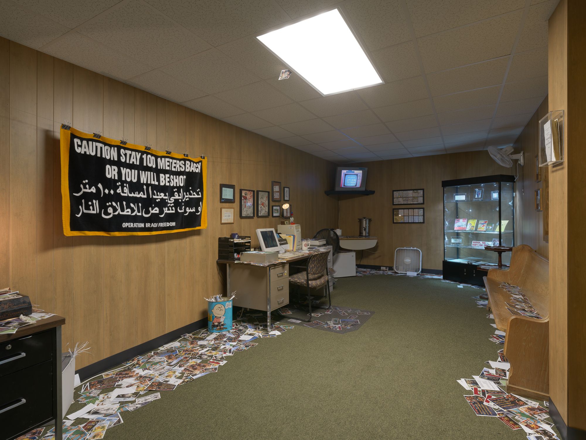 Photograph of exhibit taken from the corner of the room. Floor is littered with pamphlets.