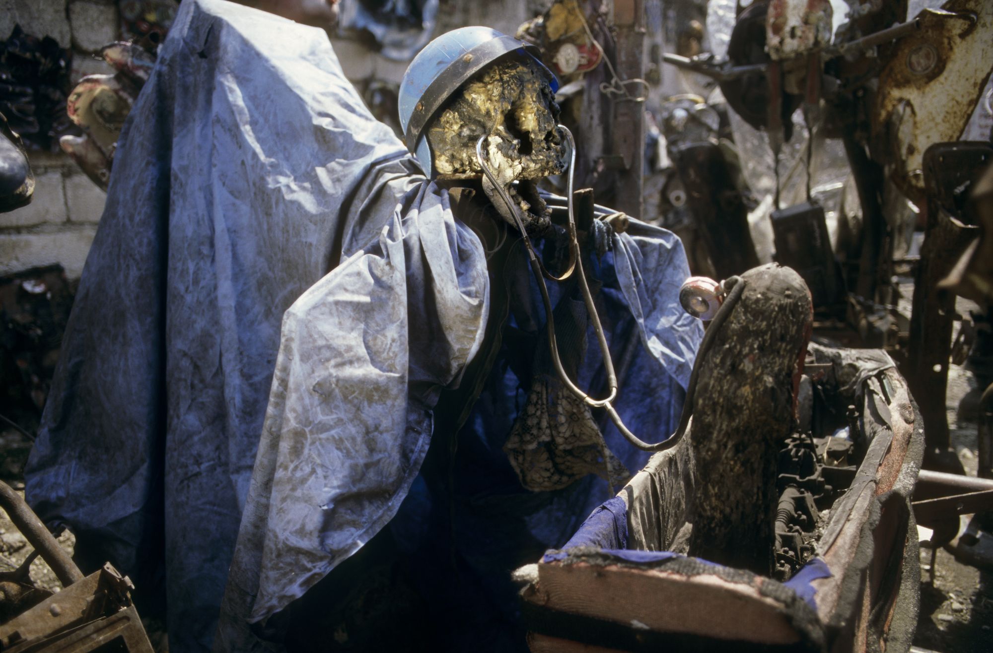 Sculpture of golden skeleton with blue military helmet, draped in blue tarp.