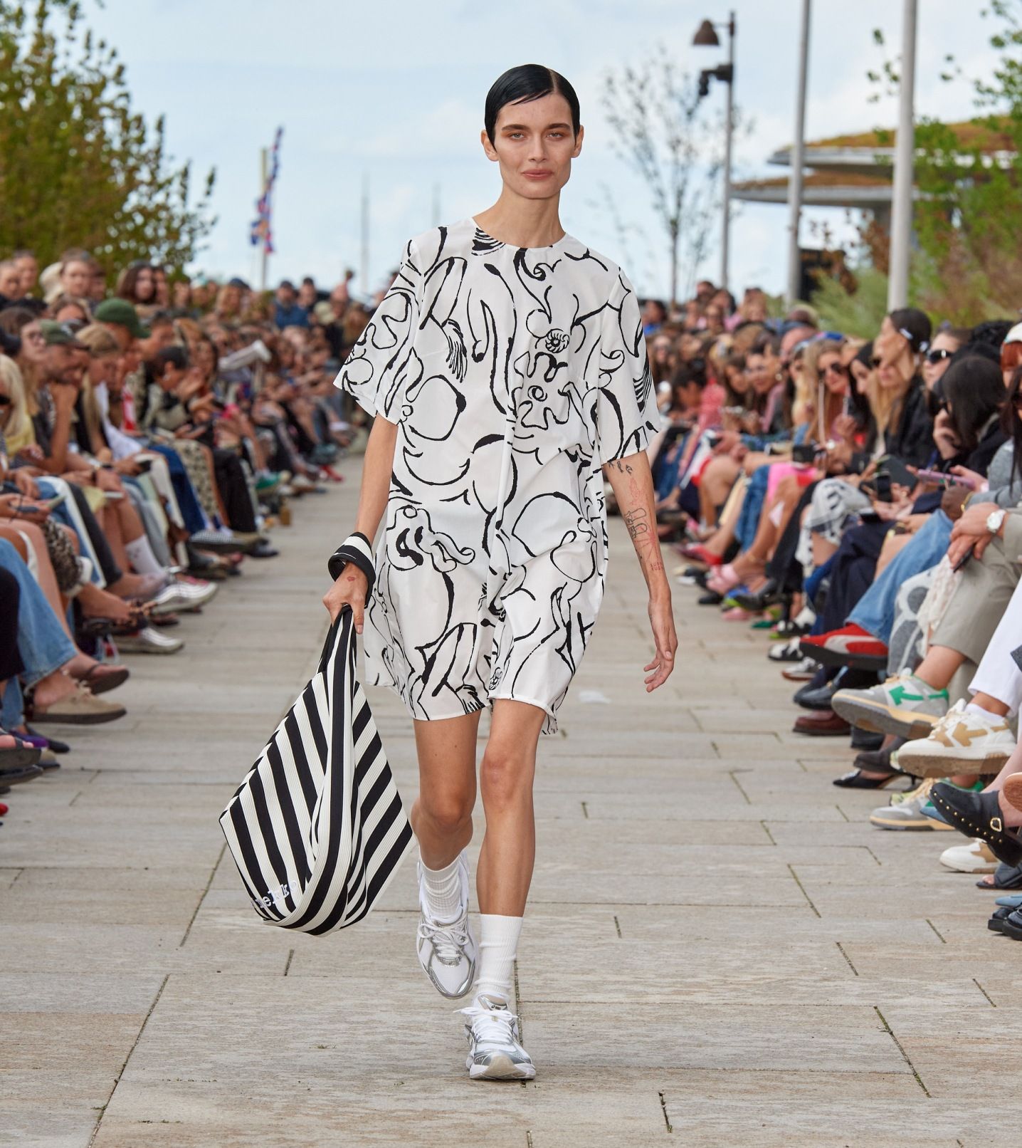 Model walking on the catwalk of the fashion show dressed in a black and white Blossoming Baluns dress.