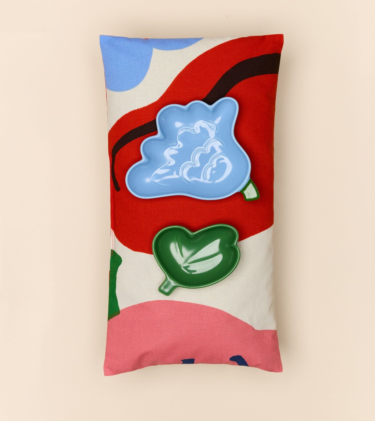 Two plates inspired by Kukasta kukkaan print, placed on a pillow with the same print.