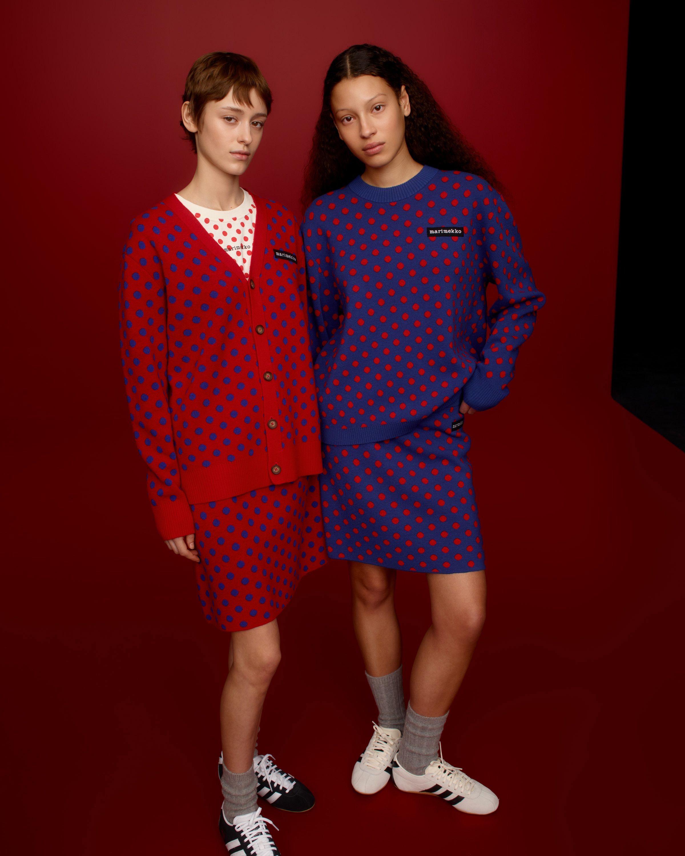 Two models wearing Marimekko Kioski knits and knitted skirts in red and purple Pallo print.