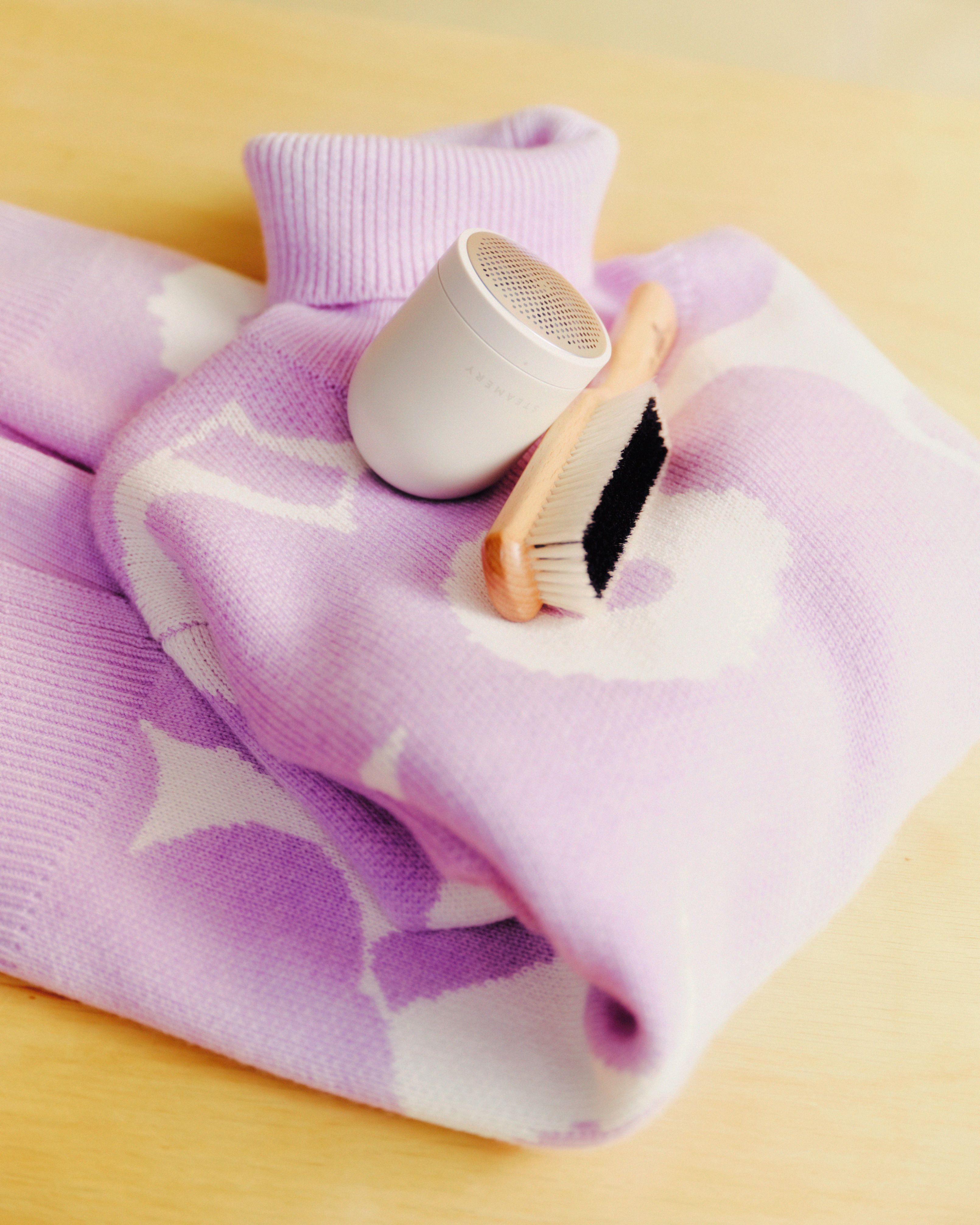 Neule Unikko-kuviolla ja neuleen hoitoon tarkoitetut tuotteet: Kent-vaateharja ja Steamery-nukkaleikkuri