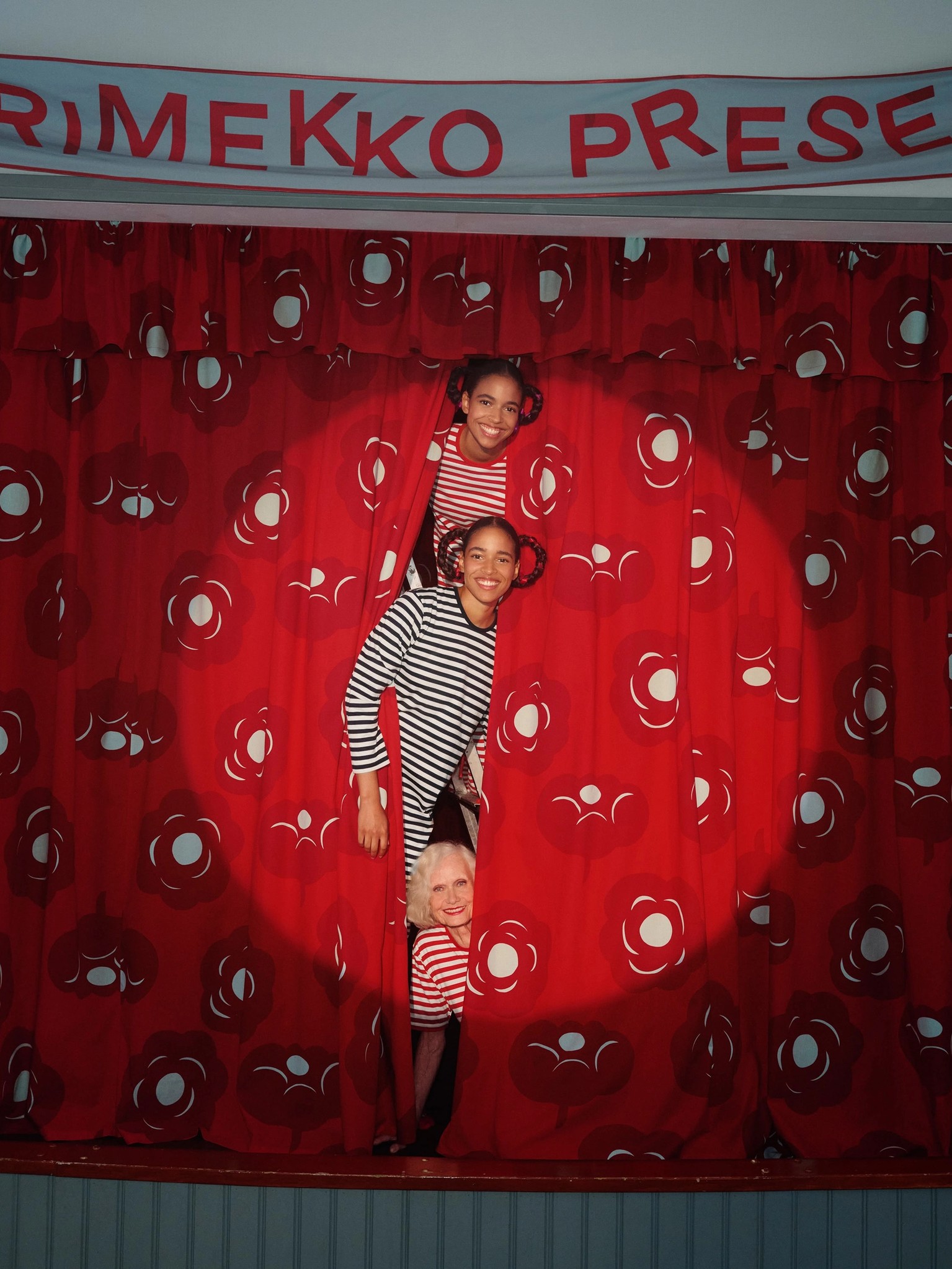 Three models peaking through a curtain wearing red and black Tasaraita shirts.