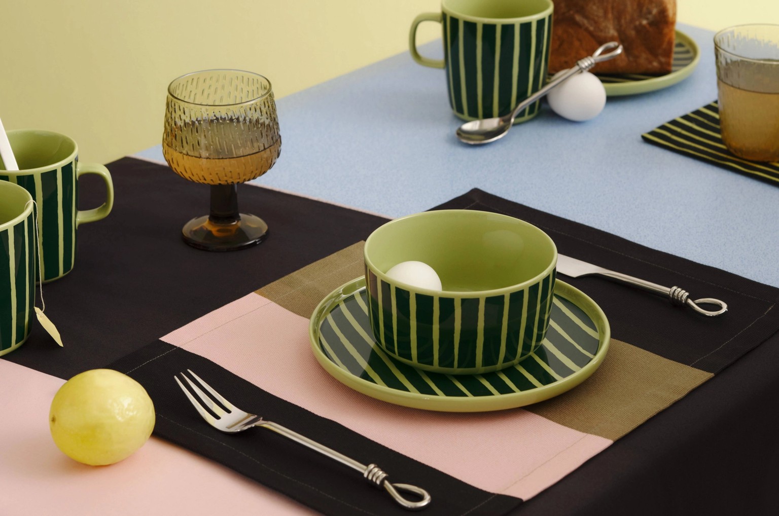 Tablesetting with Marimekko Oiva tableware in green Piccolo print on a tablecloth in Hennika print.
