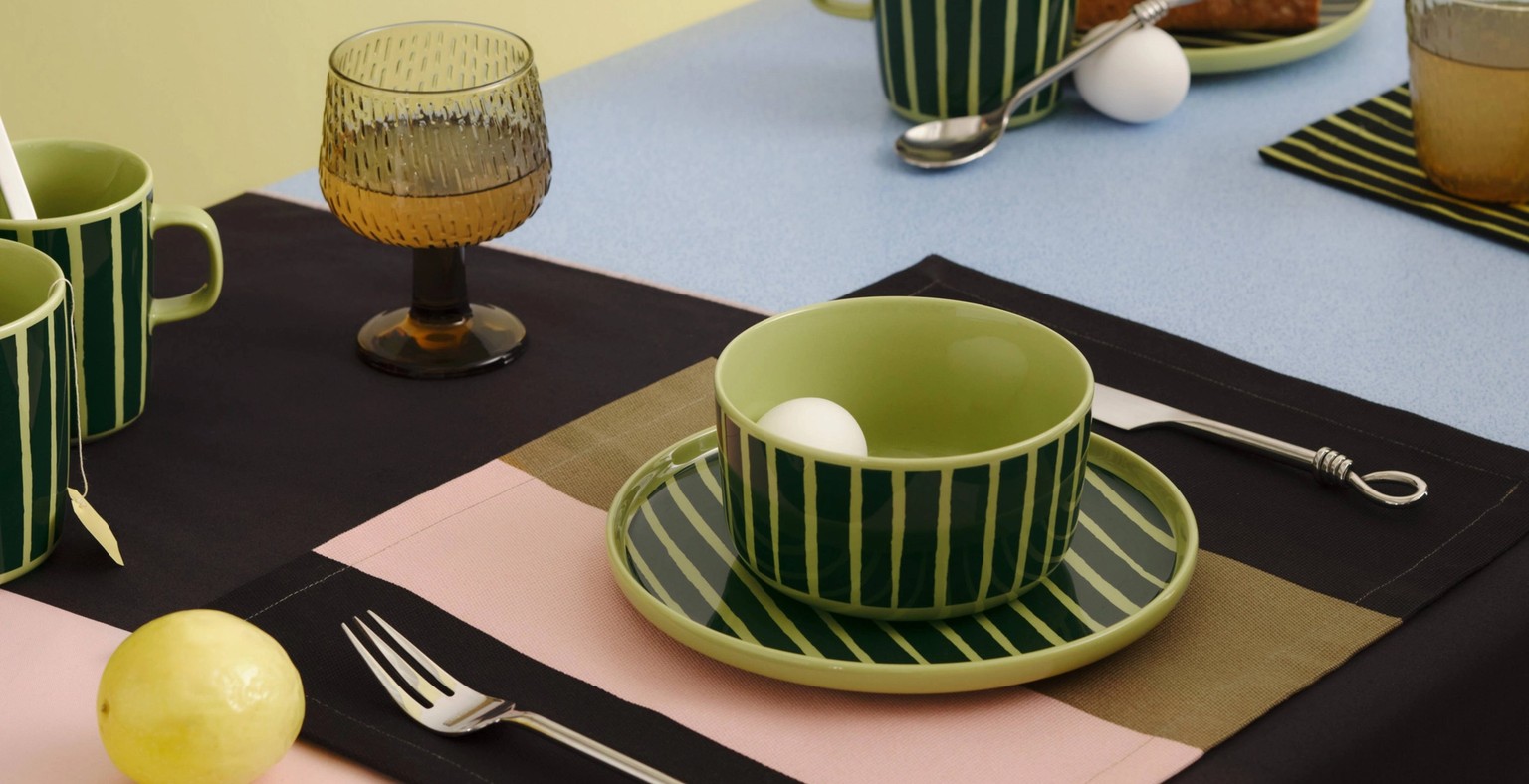 Tablesetting with Marimekko Oiva tableware in green Piccolo print on a tablecloth in Hennika print.