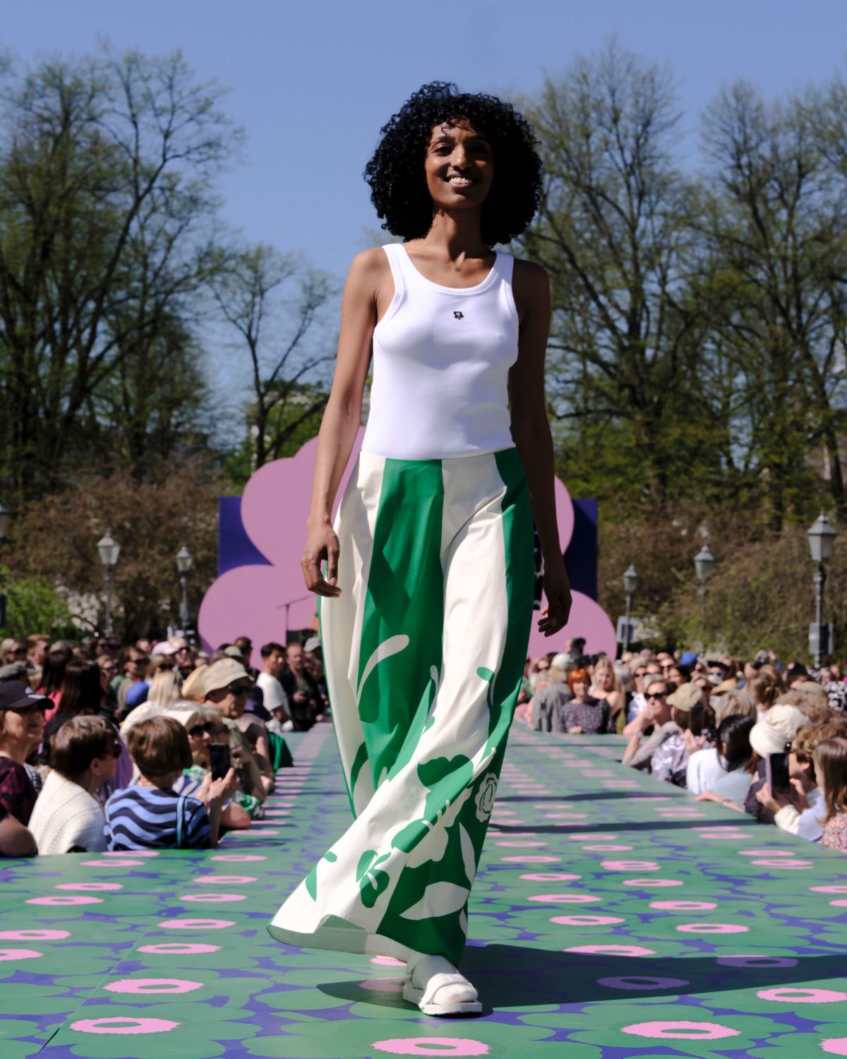 Model wearing white top with Unikko detail and green and white skirt
