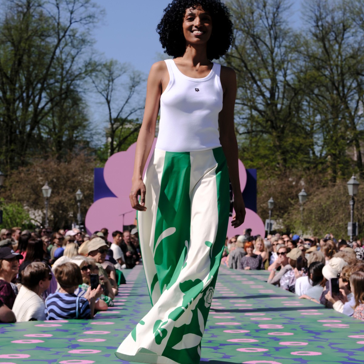 Model wearing white top with Unikko detail and green and white skirt