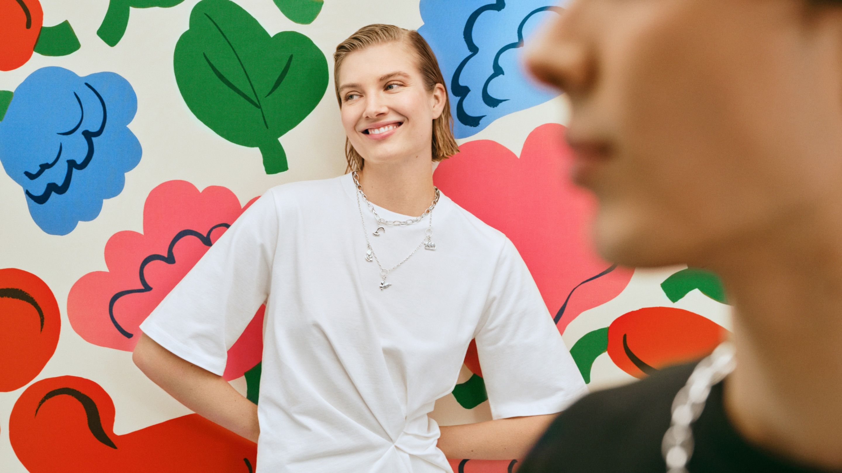 Two model posing infront of Kukasta kukkaan print with a Kalevala x Marimekko Garden necklaces.
