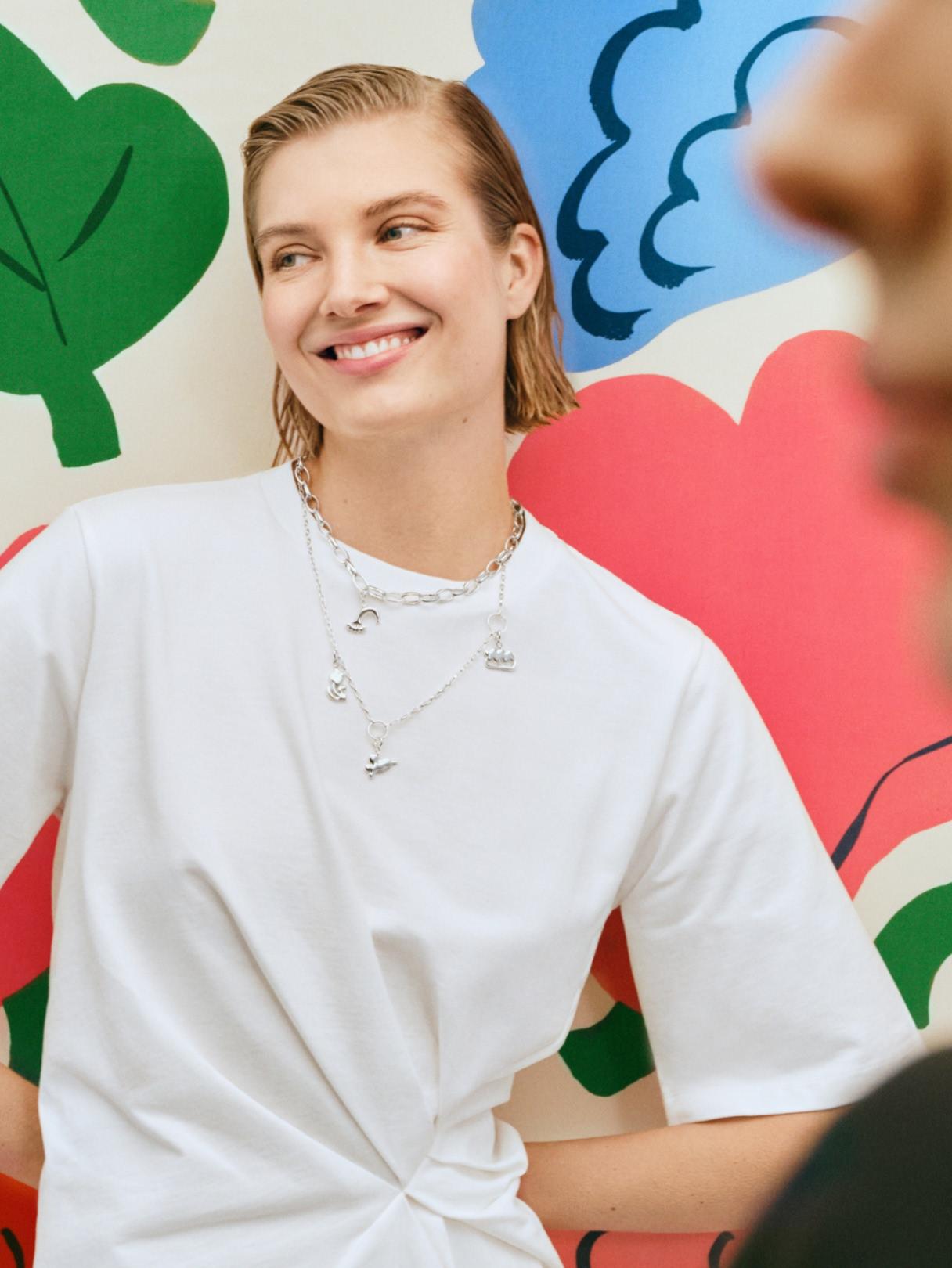 Kaksi malli poseeraa Kukasta kukkaan -printin edessä ja heillä on Kalevala x Marimekko Garden -kaulakoru.