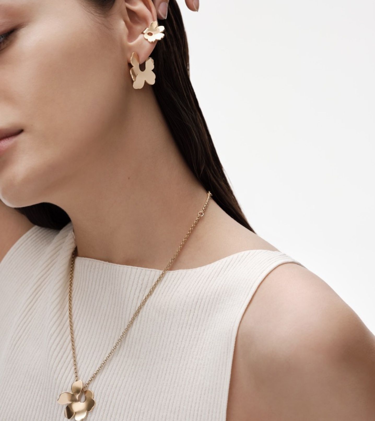 Model wearing Kalevala x Marimekko ear cuff, earring and necklace in gold.