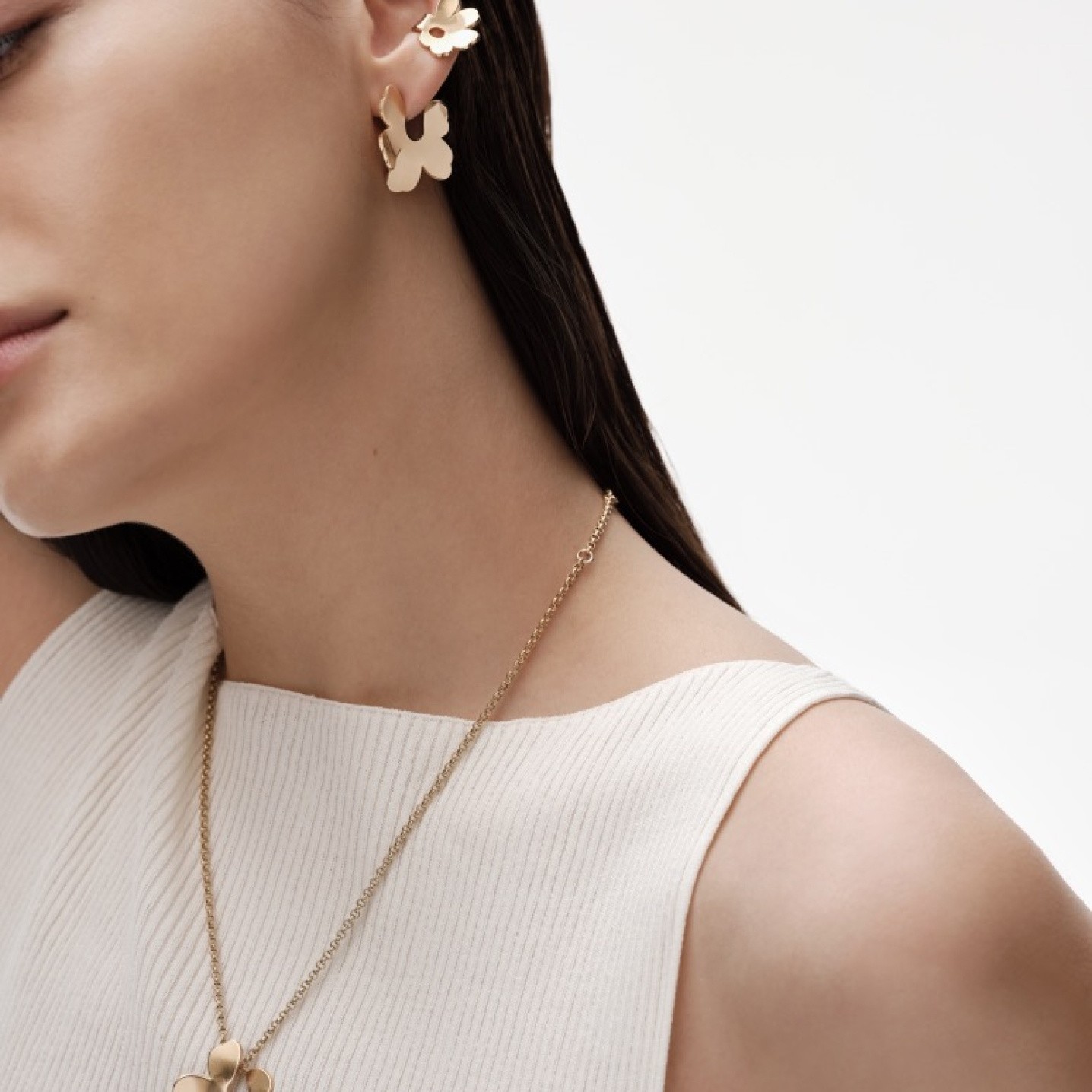 Model wearing Kalevala x Marimekko ear cuff, earring and necklace in gold.