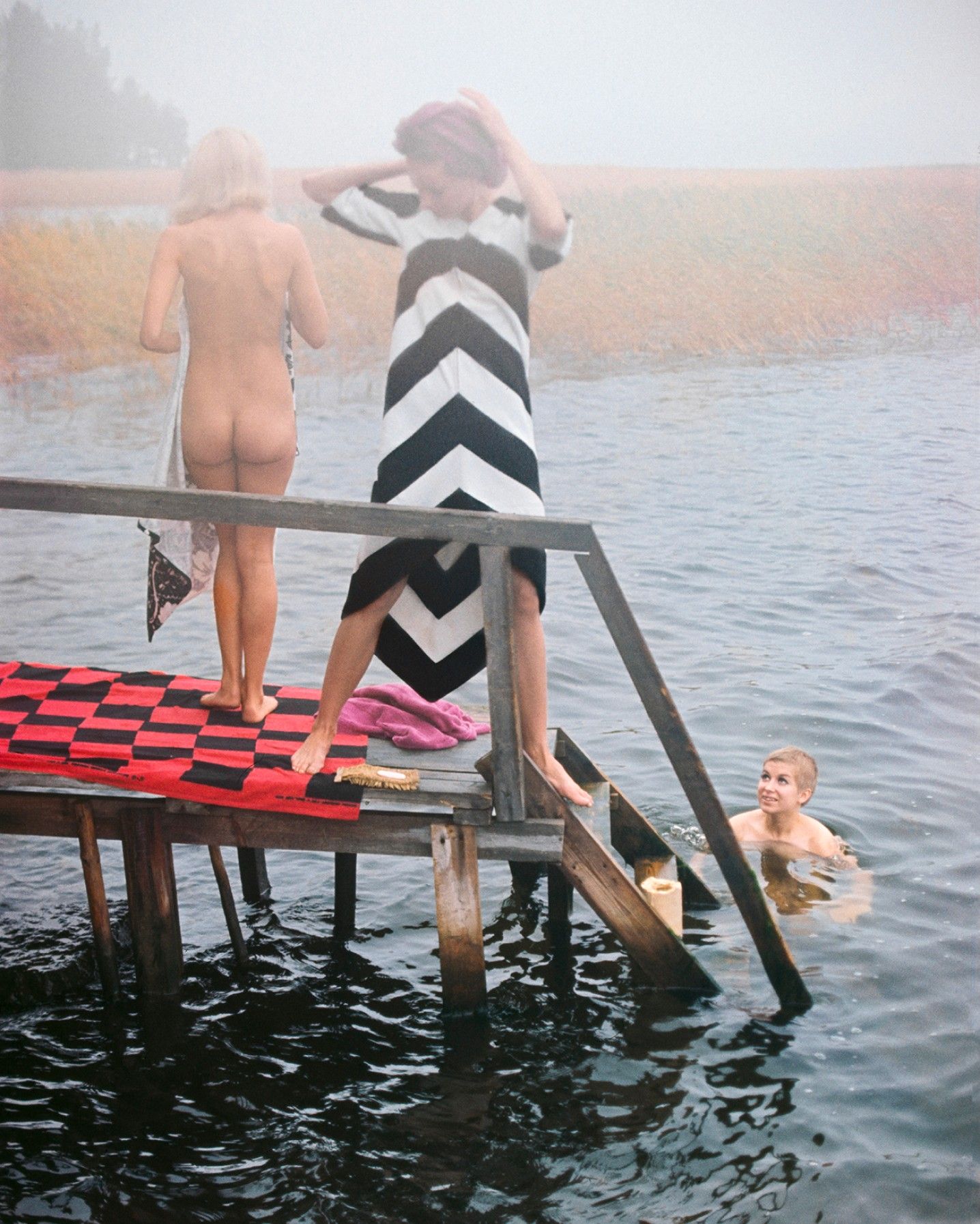 Photo by Tony Vaccaro of people standing on a pier and swimming.