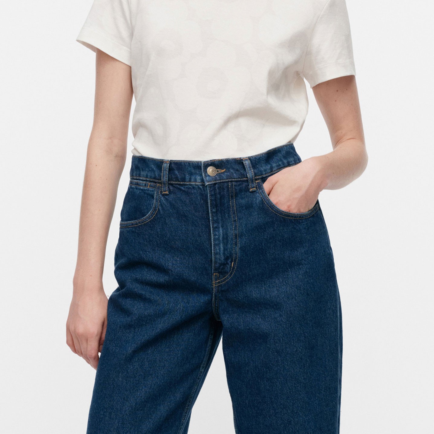 Model wearing dark blue Marimekko Maridenim jeans and a white t-shirt with Unikko print.