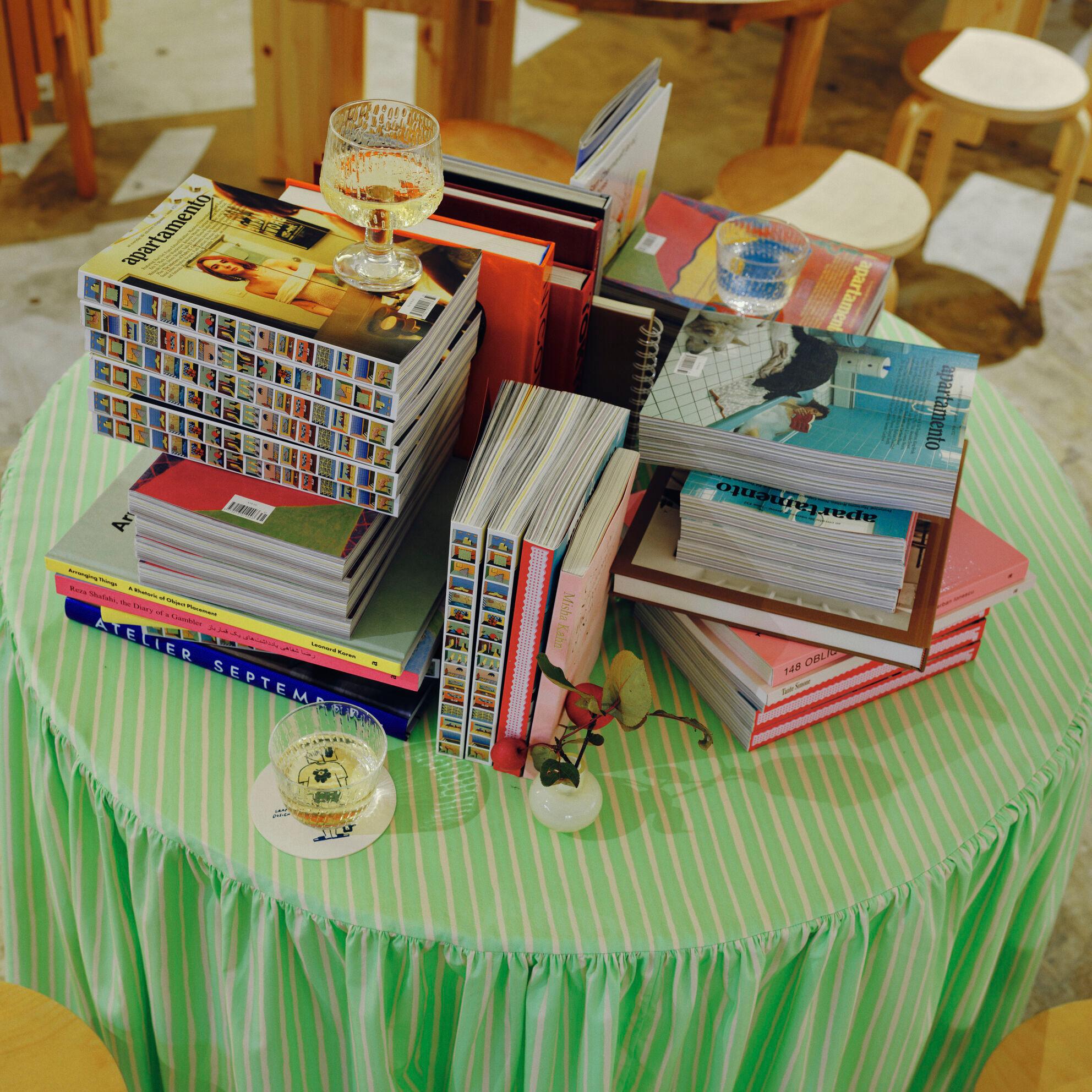 Book installation decorated with the Syksy glass series and a green tablecloth with the Jokapoika pattern