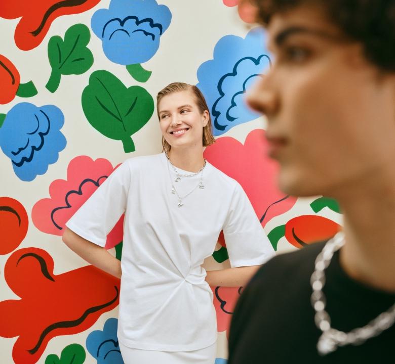 Zwei Models posieren vor dem Print „Kukasta kukkaan“ mit einer Halskette von Kalevala x Marimekko Garden.