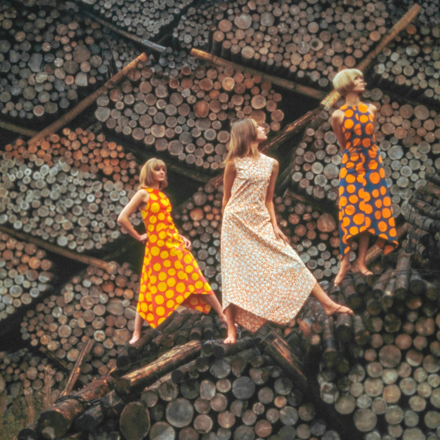 Foto von Tony Vaccaro von drei Models, die Marimekko-Kleider tragen und auf einem Holzstapel stehen.
