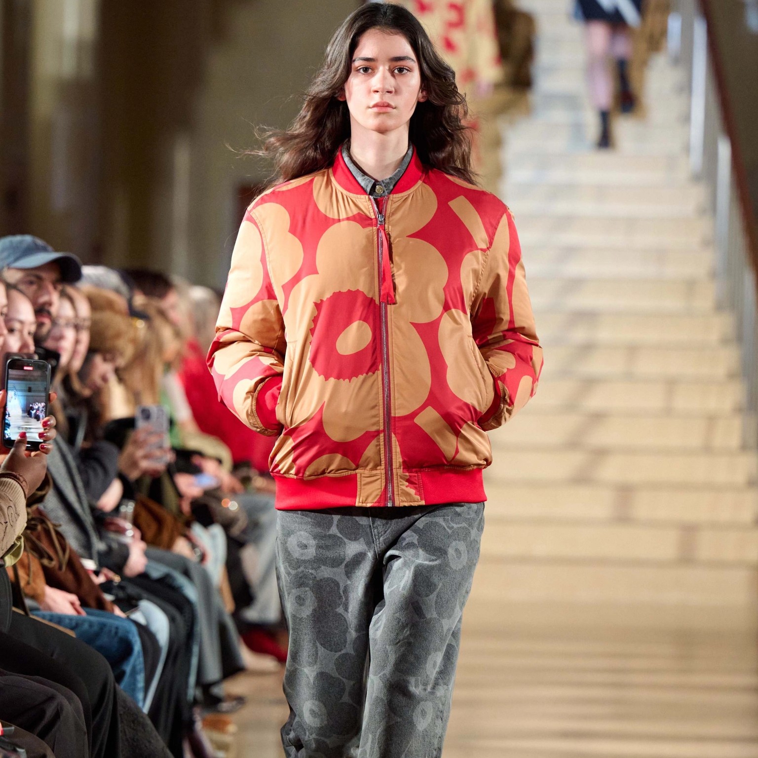 Model wearing a red-beige padded coat in Unikko-print.