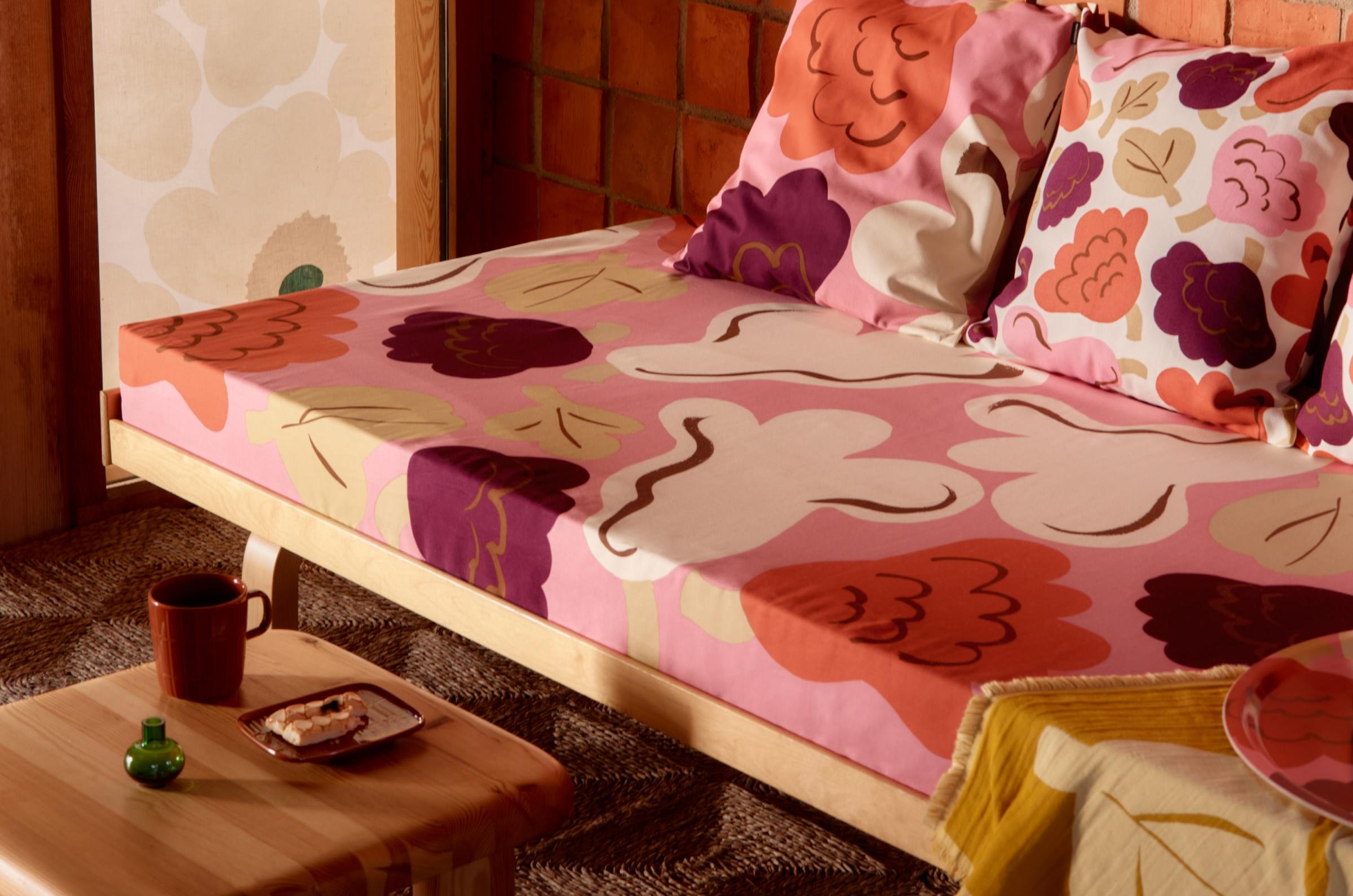 A daybed covered with Kukasta Kukkaan fabric, topped with matching cushion covers.