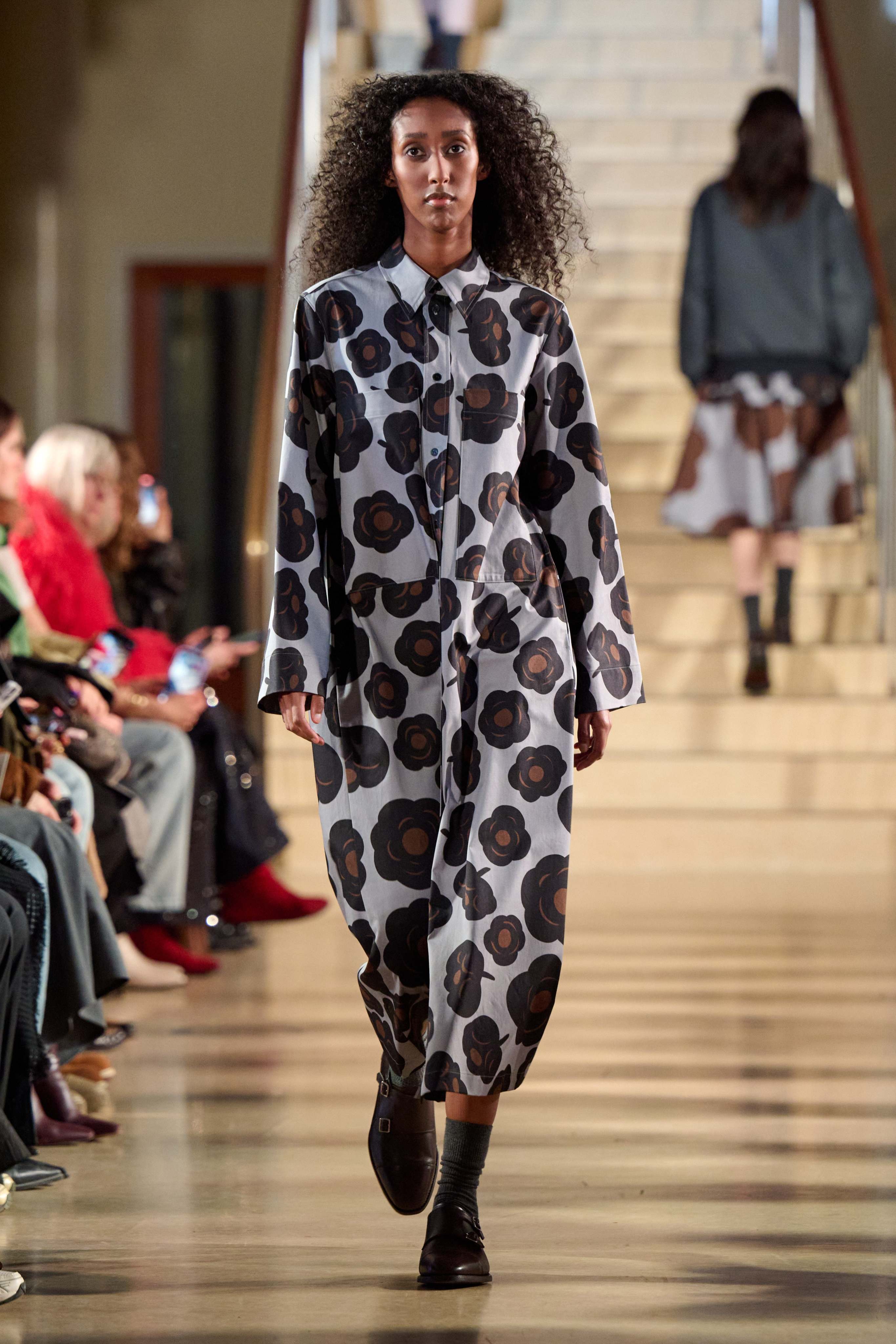 A model walking in Marimekko's fashion show wearing Tumma-printed long dress