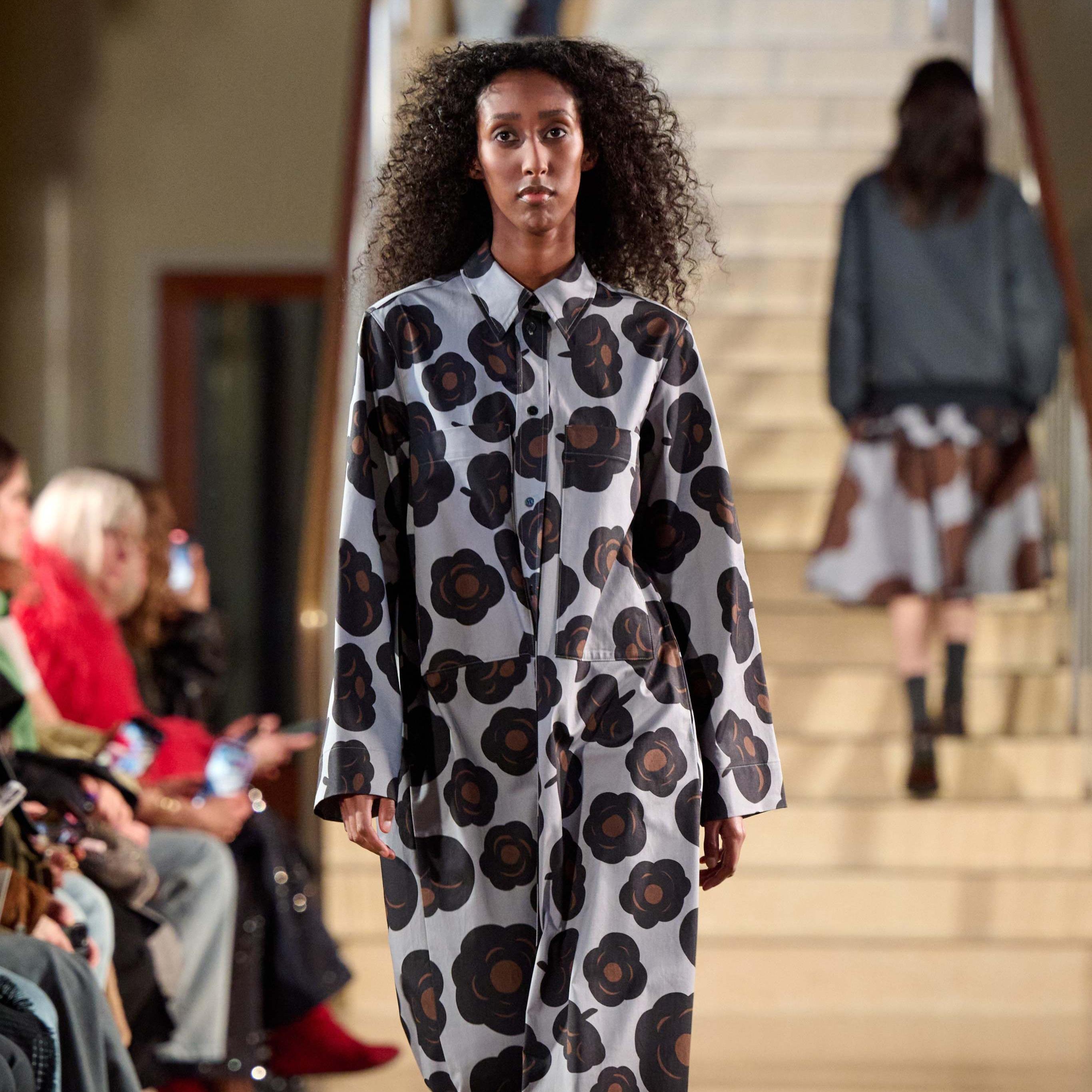 A model walking in Marimekko's fashion show wearing Tumma-printed long dress