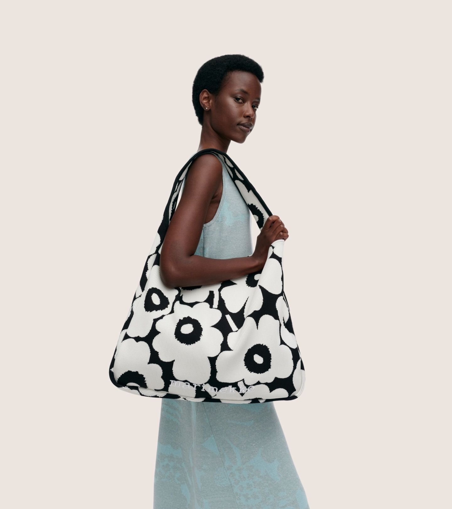 Model holding a black and white knitted bag in Unikko print.