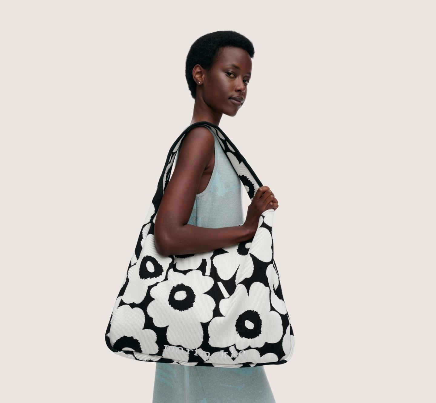 Model holding a black and white knitted bag in Unikko print.