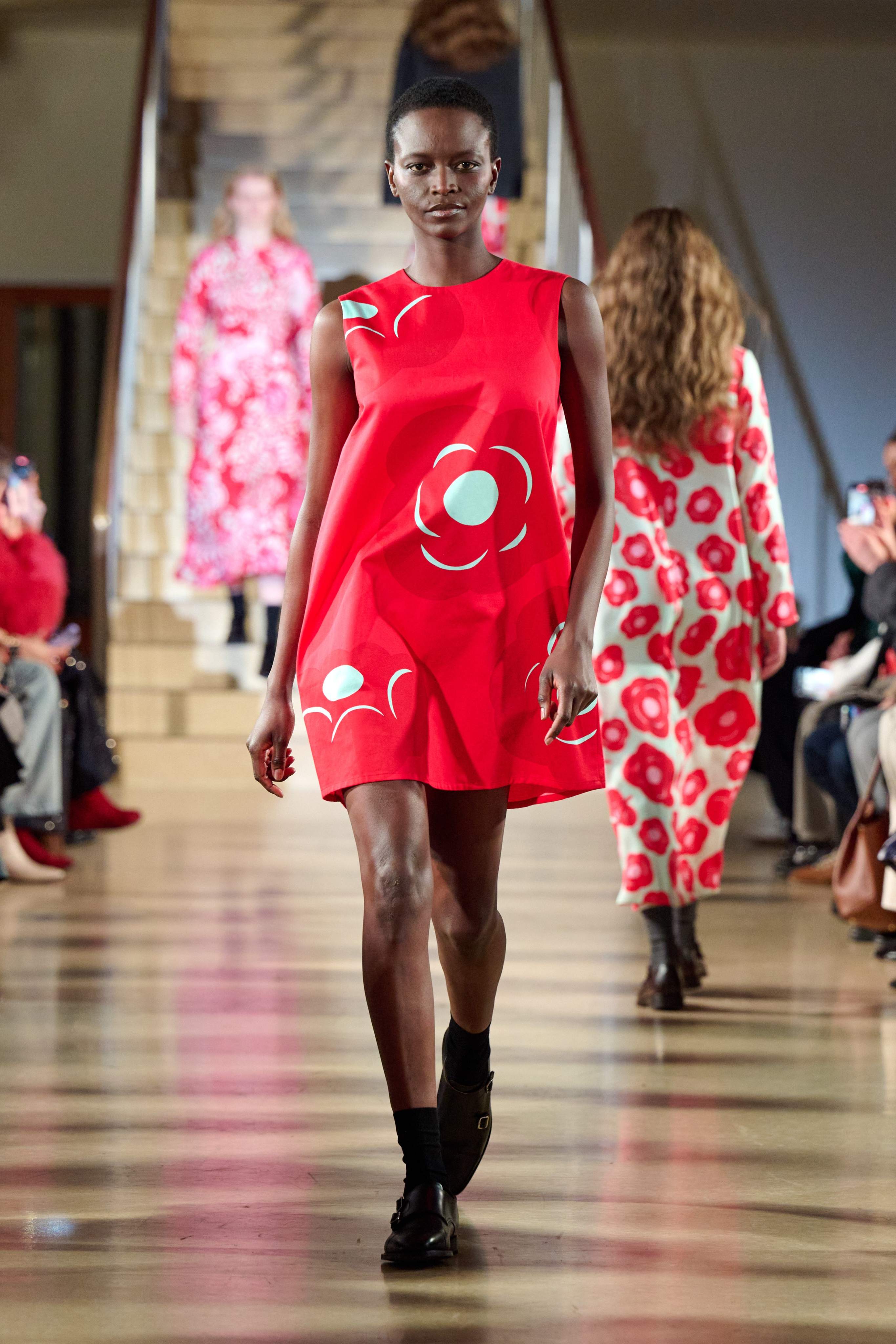 A model walks in the Marimekko fashion show wearing a bright red Marimini dress
