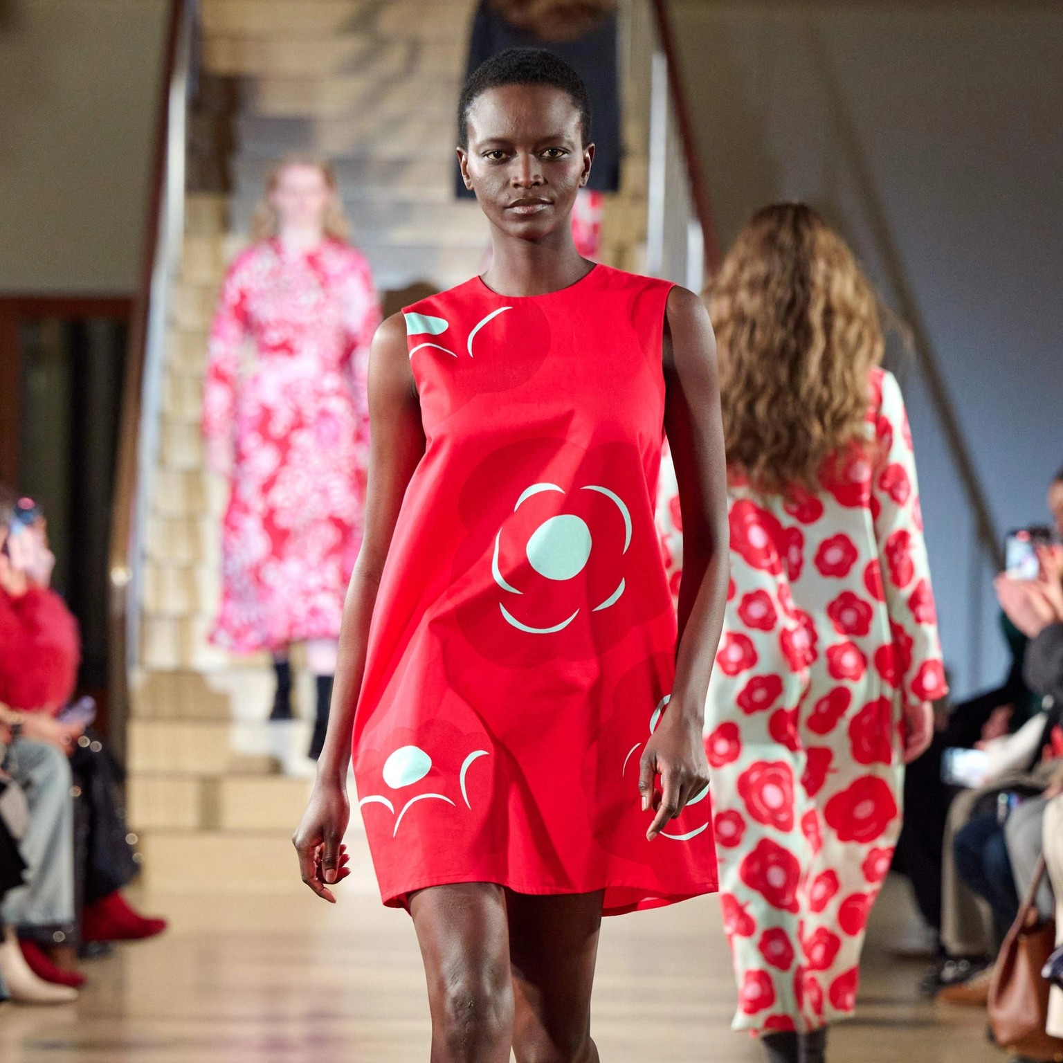 A model walks in the Marimekko fashion show wearing a bright red Marimini dress