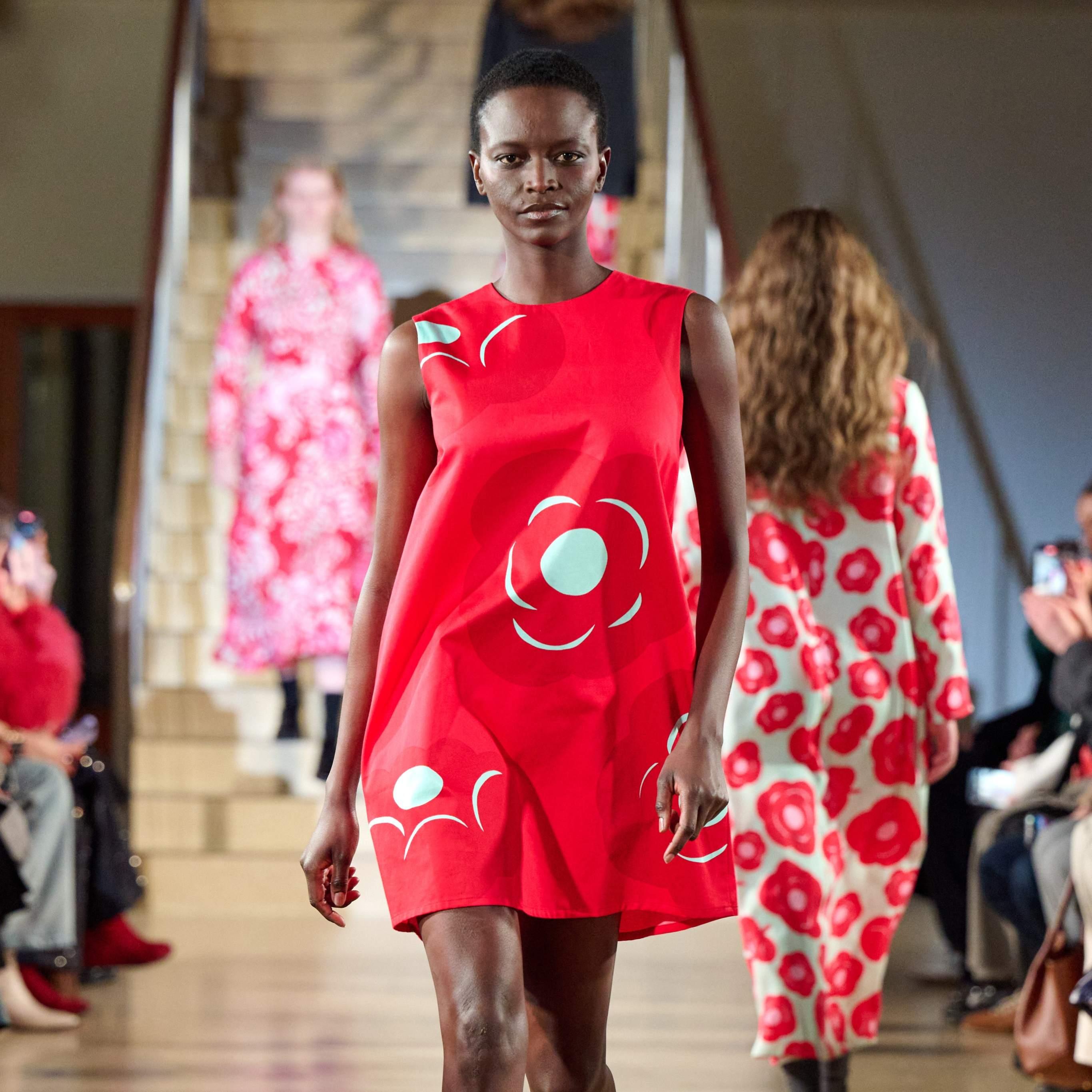 A model walks in the Marimekko fashion show wearing a bright red Marimini dress