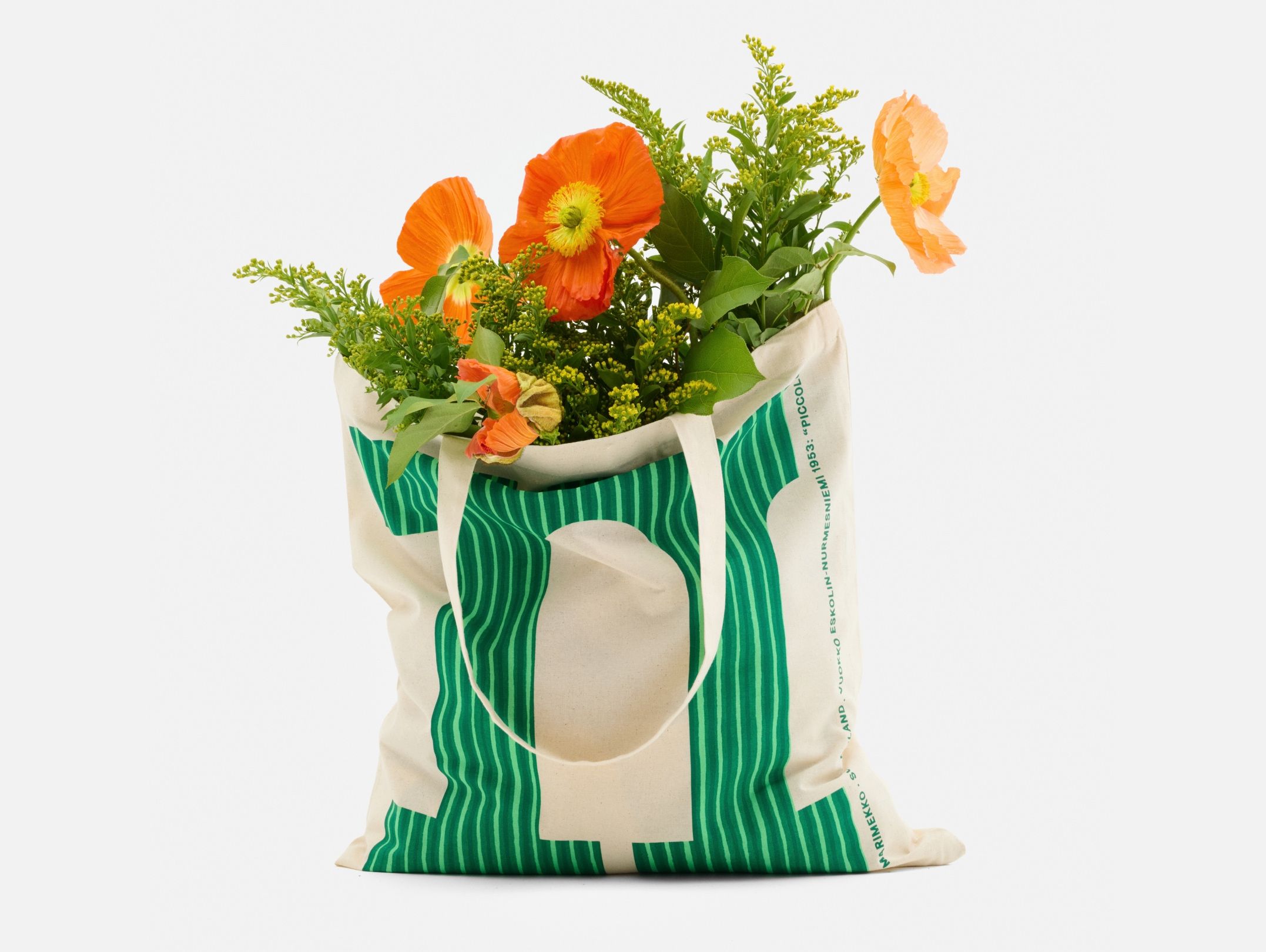 Kangaskassi, jossa on Piccolo-painatuksella kuvioitu vihreä M-kirjain ja kukkia.