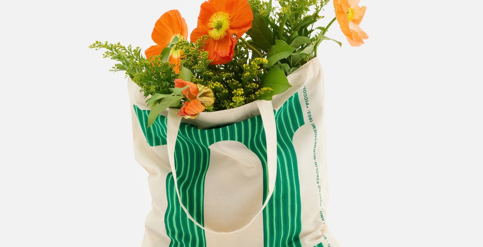 Logo tote, with a green letter M in Piccolo print, filled with flowers.