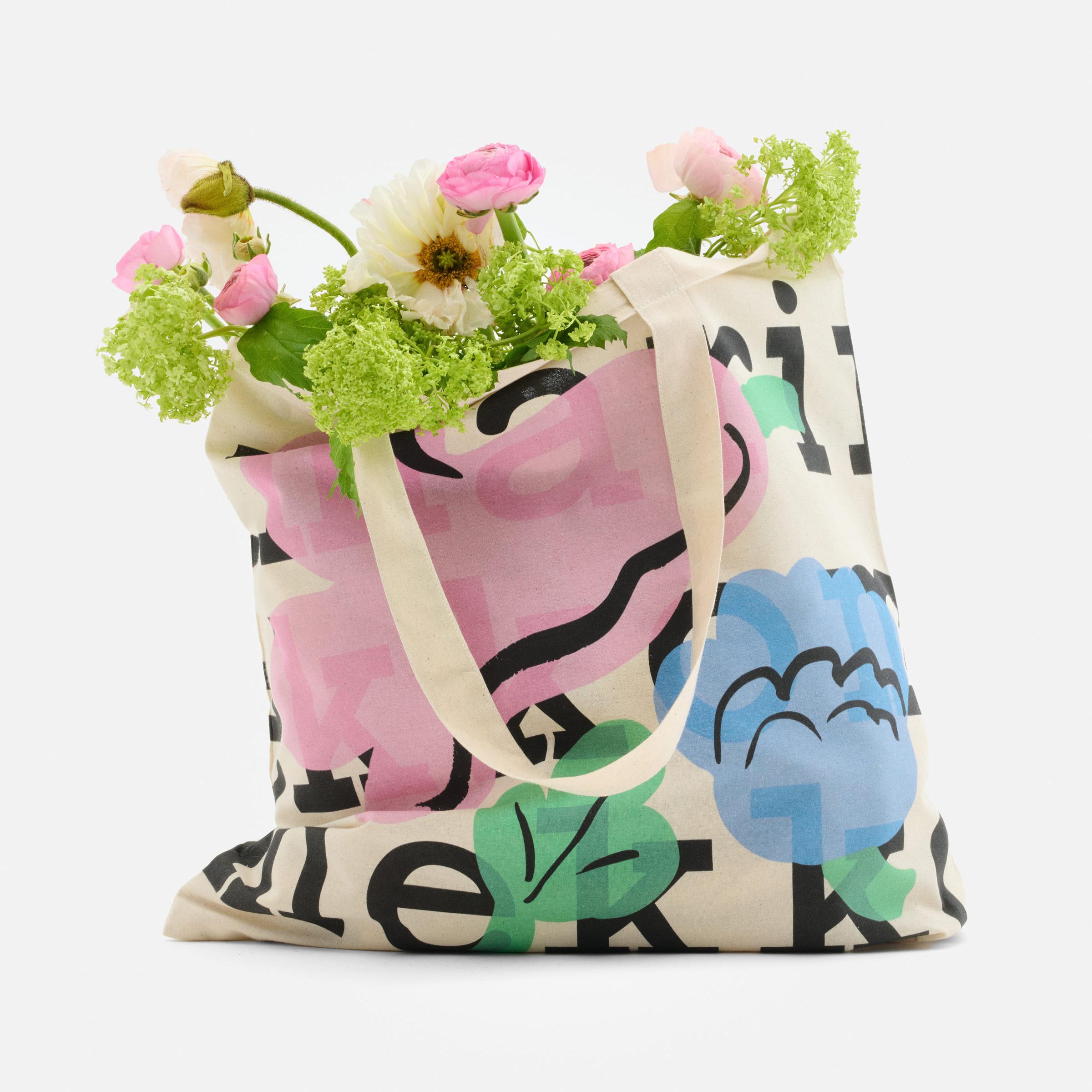 Logo tote, with a logo text and Kukasta kukkaan print, filled with flowers.