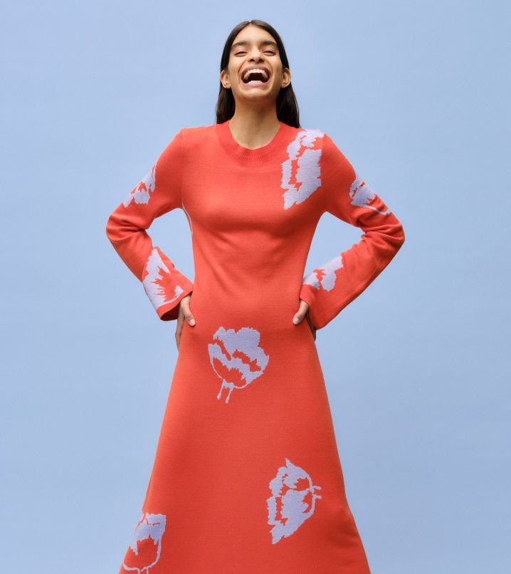 A smiling model dressed in a red Myski patterned knitted dress.