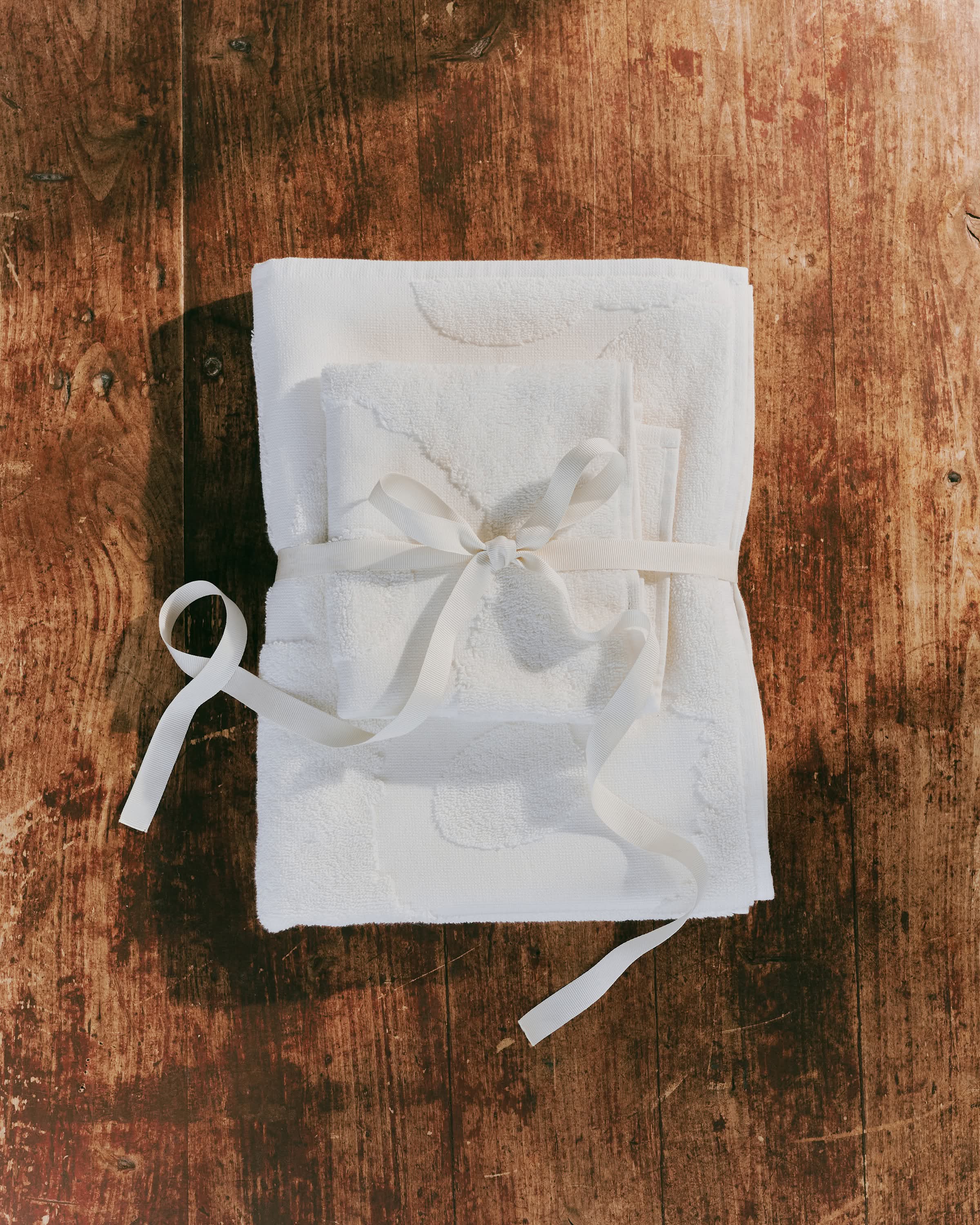White Unikko towels folded into a package with gift ribbon around them.